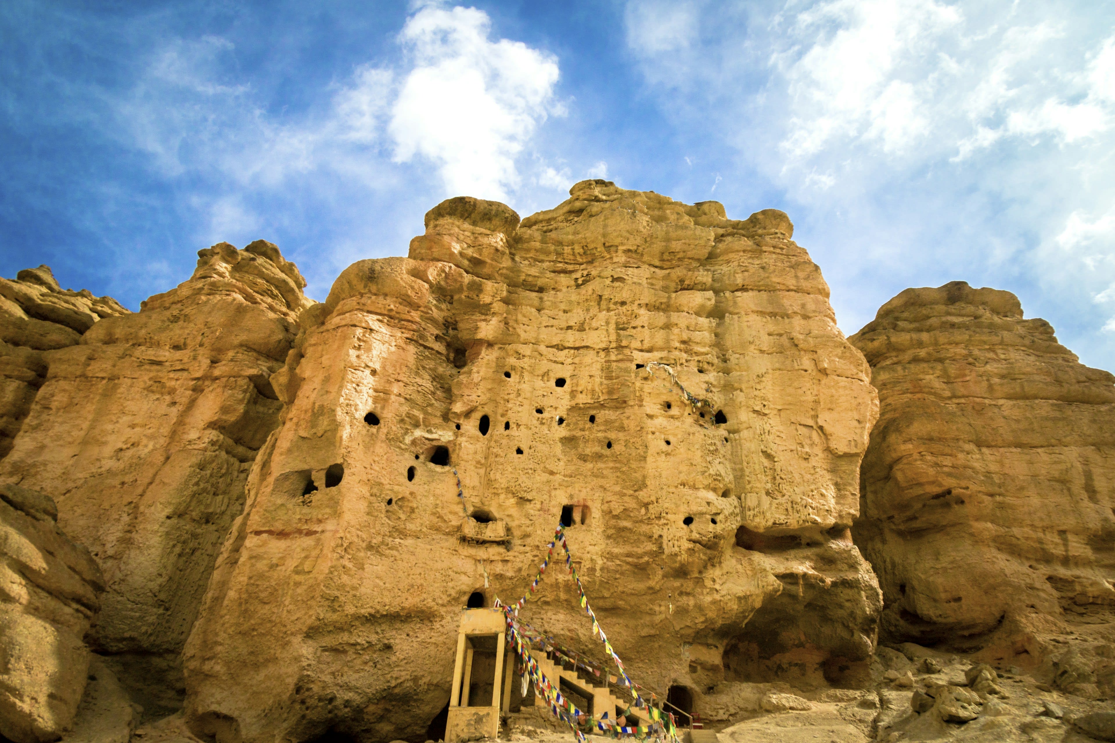 A honeycomb of ancient cave dwellings carved into a sheer sandstone cliff