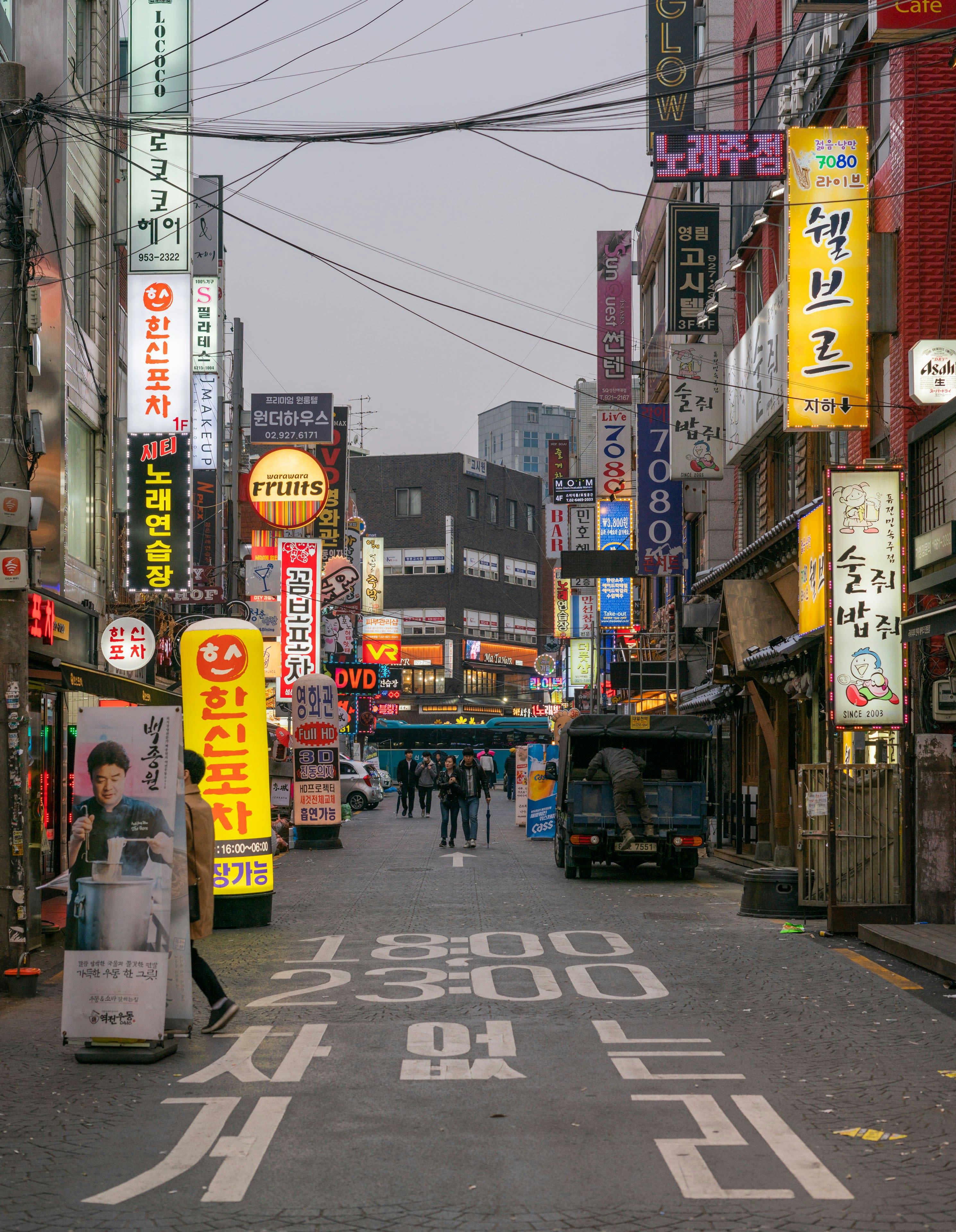 A narrow street at night stacked with illuminated Korean signage