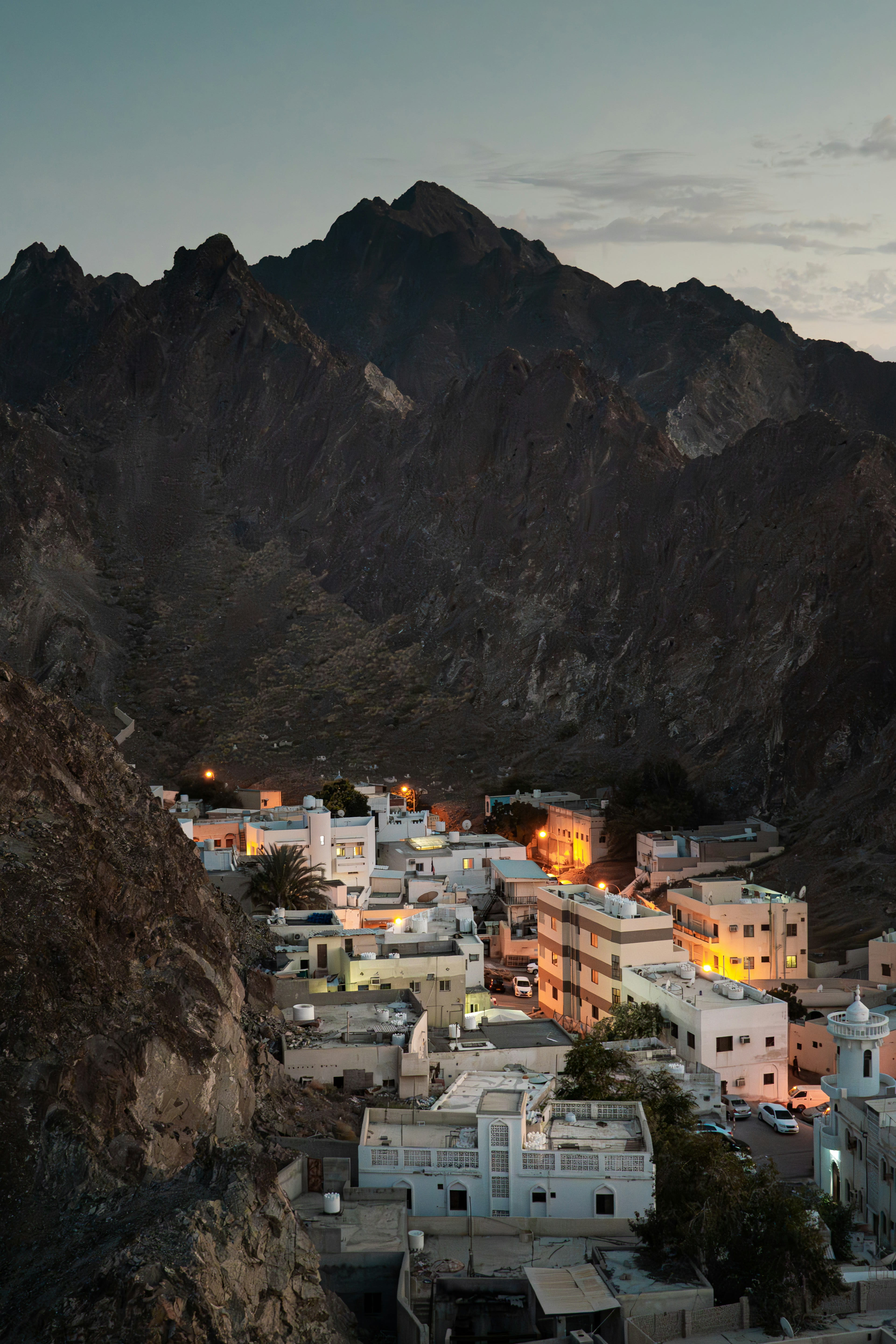 A white village glowing at dusk beneath dark mountains