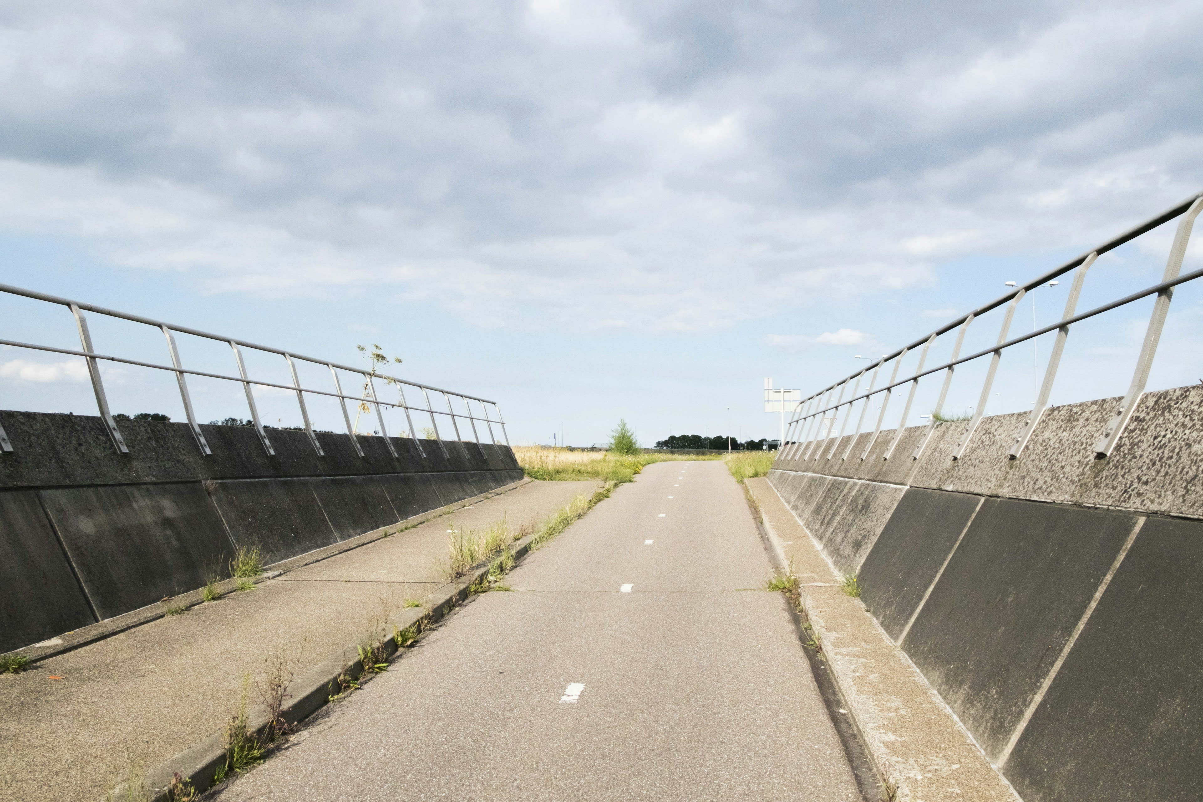 A long straight cycle path across flat open land under a grey sky