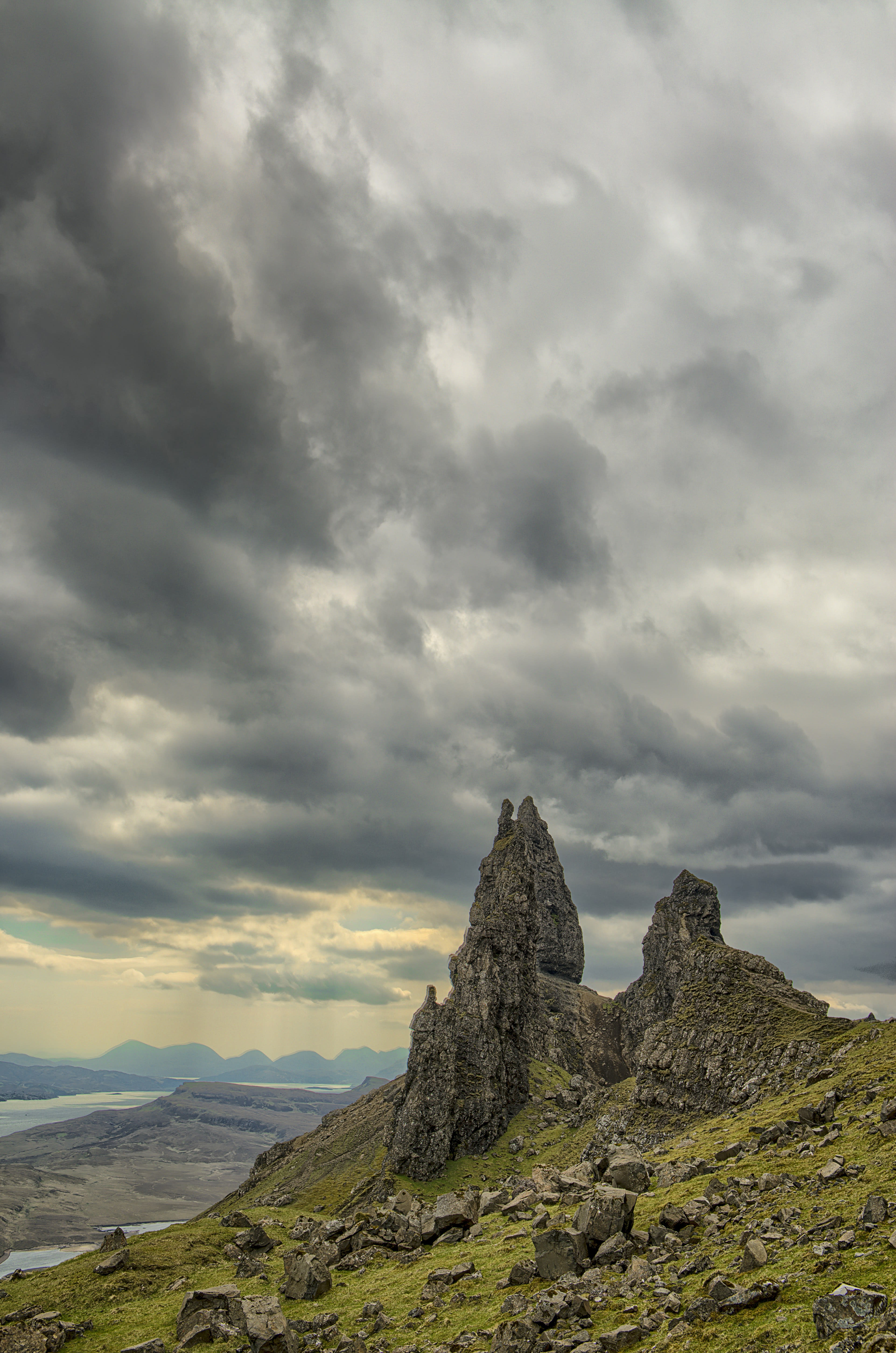 Tall basalt pinnacles on a green slope under heavy grey cloud