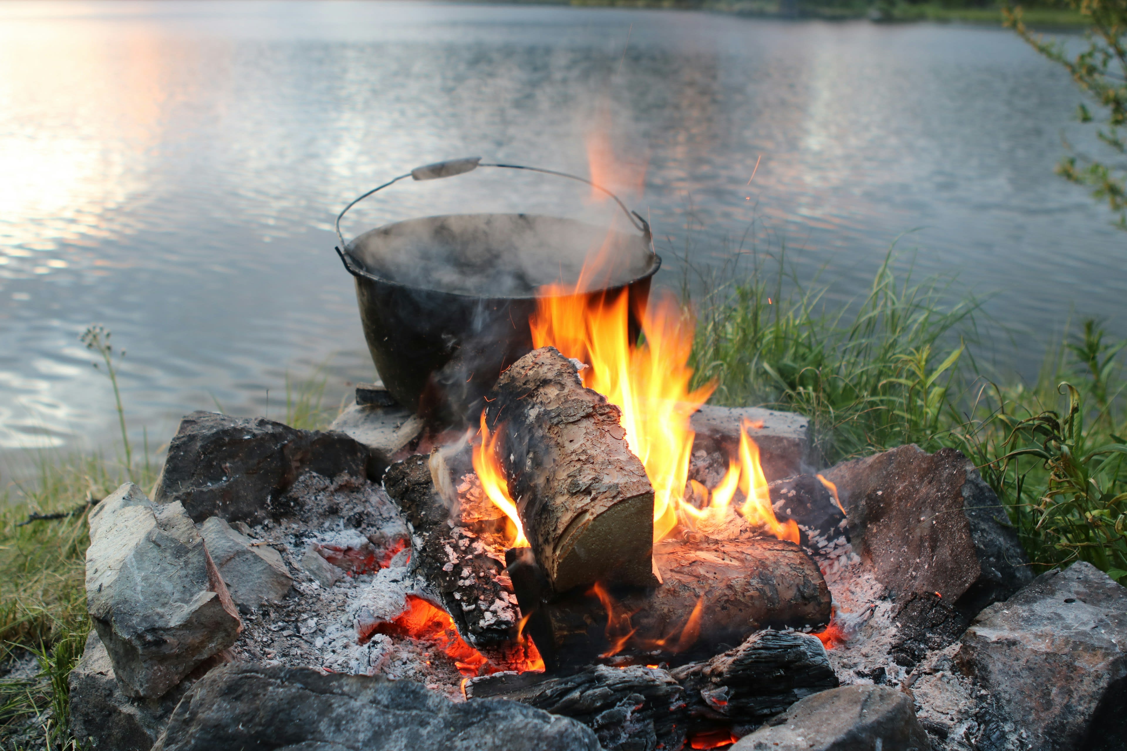 A small driftwood campfire burning on a gravel bar beside dark river water