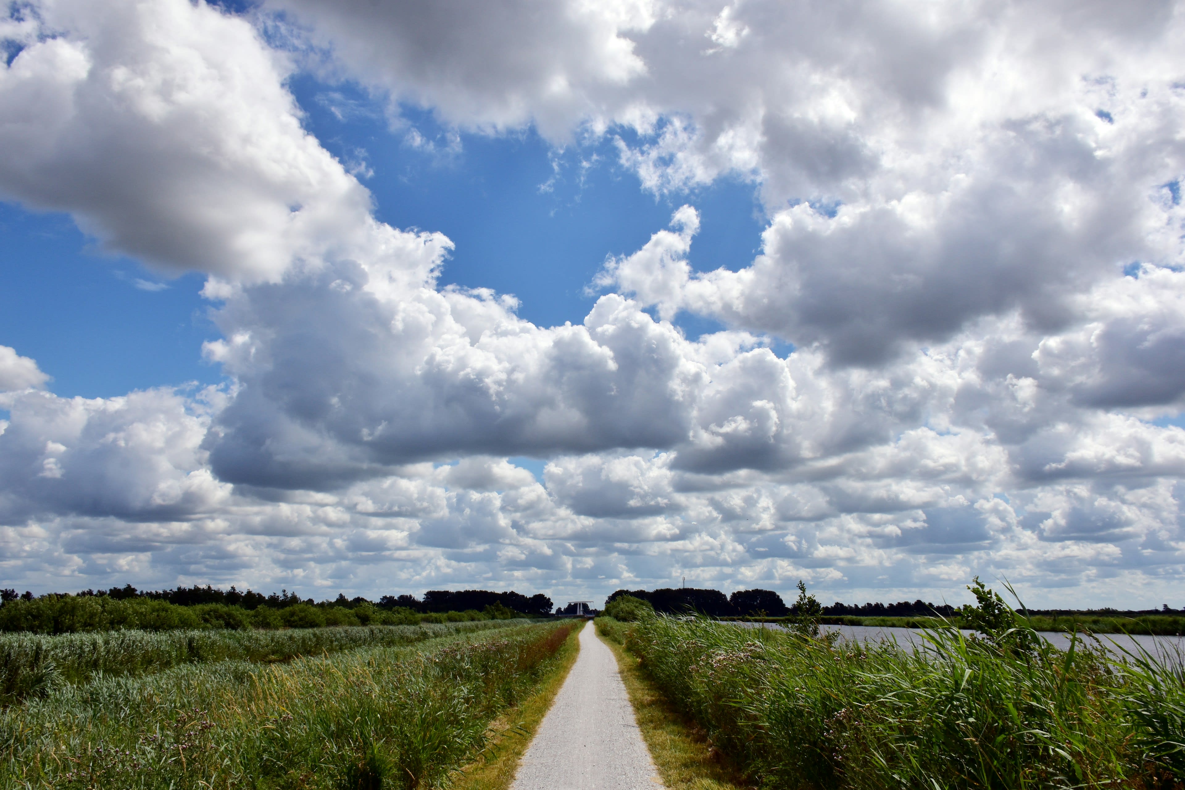 A dirt track running to the horizon under dramatic clouds