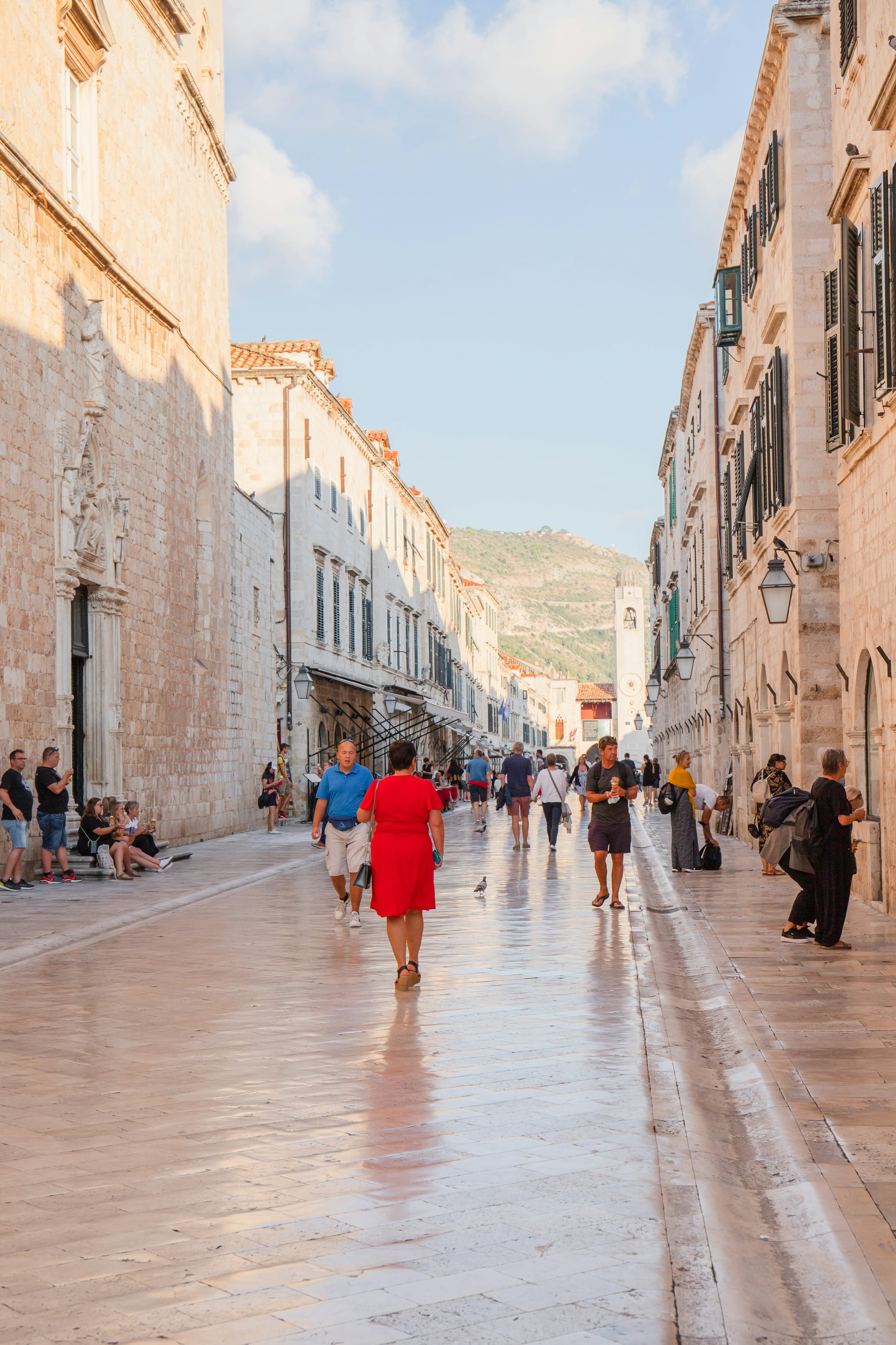 People with umbrellas walking the polished limestone Stradun in Dubrovnik