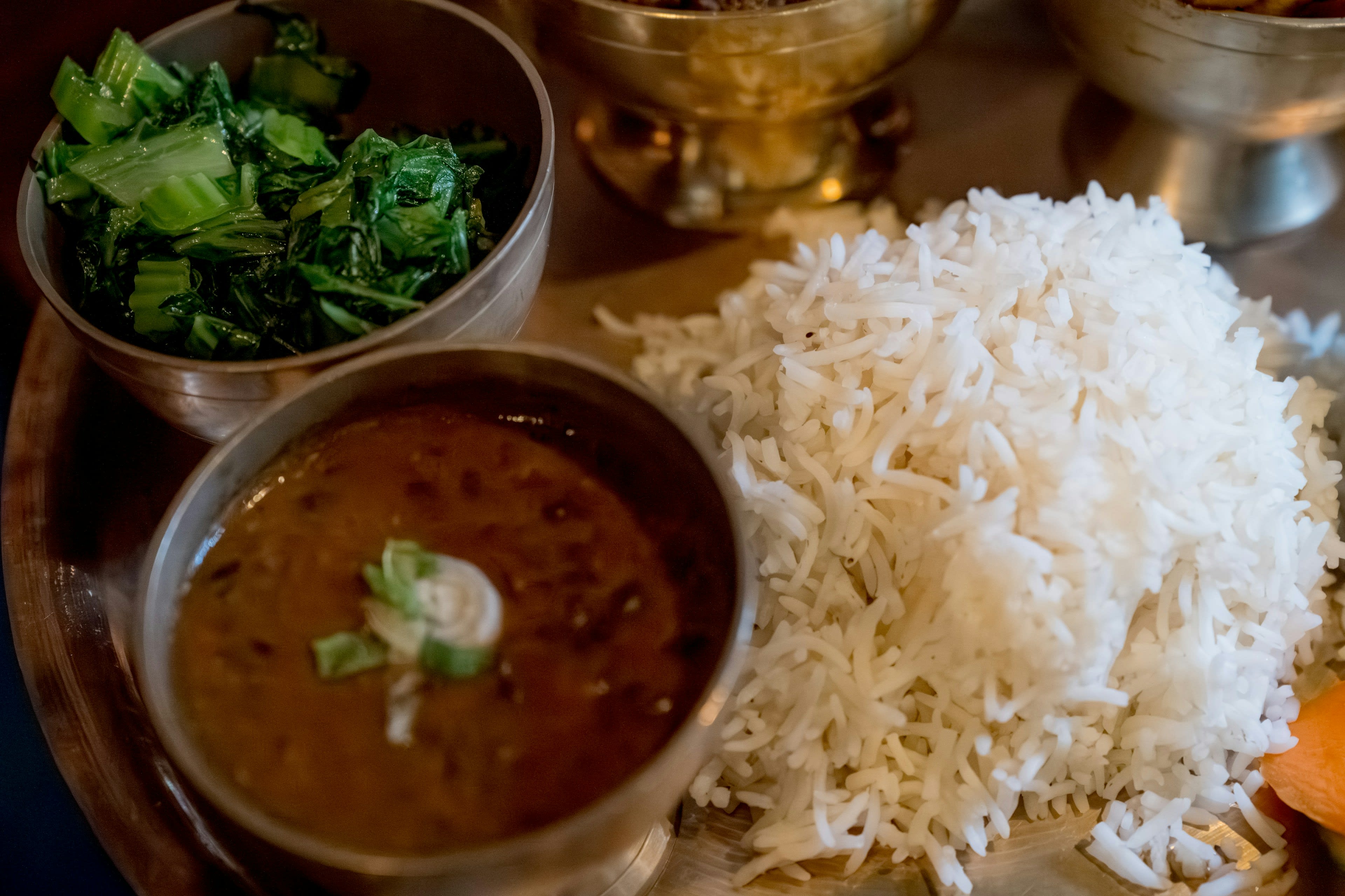 A plate of dal bhat with rice, lentils and greens