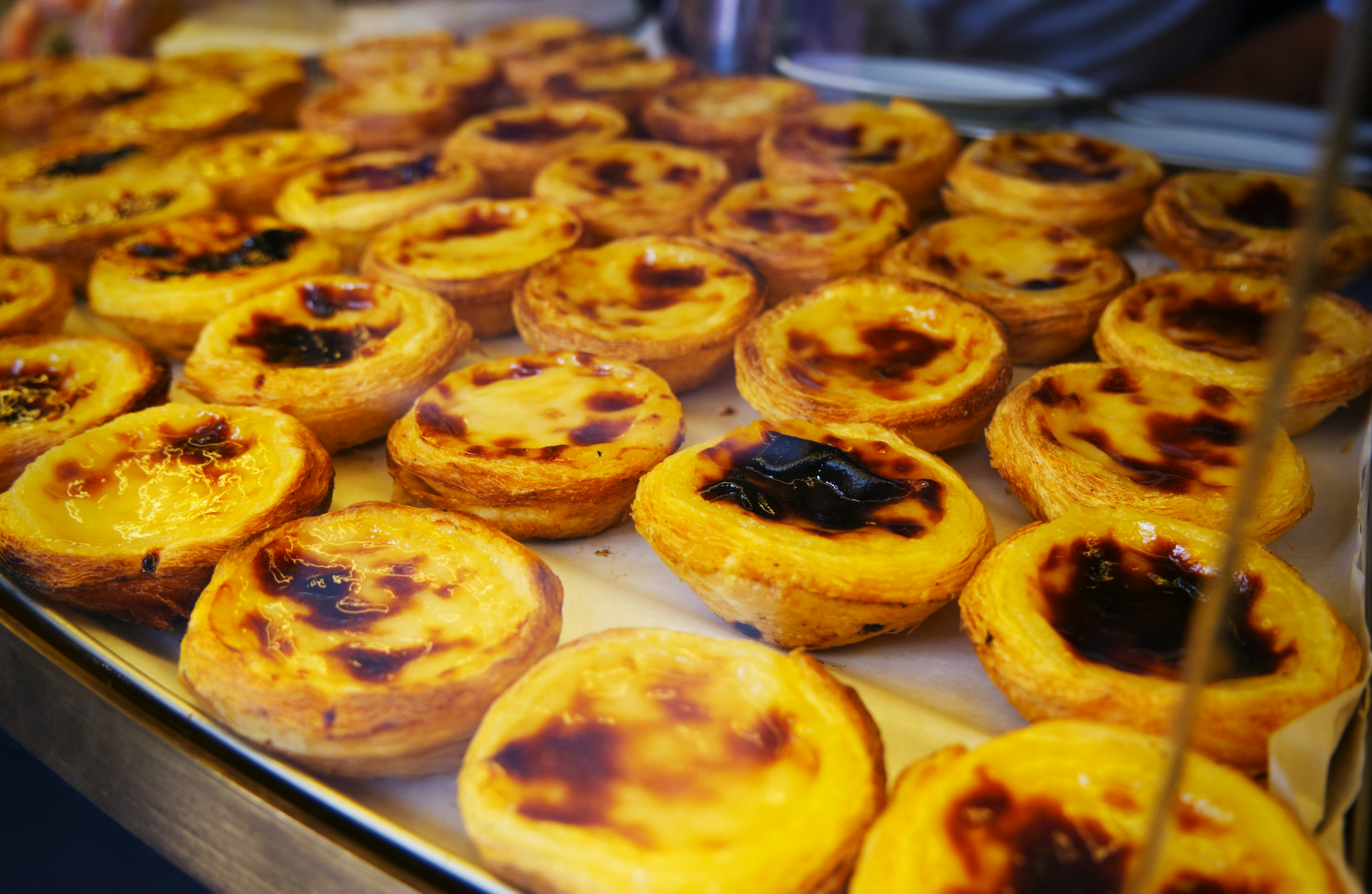 Trays of Portuguese custard tarts with caramelised tops fresh from the oven
