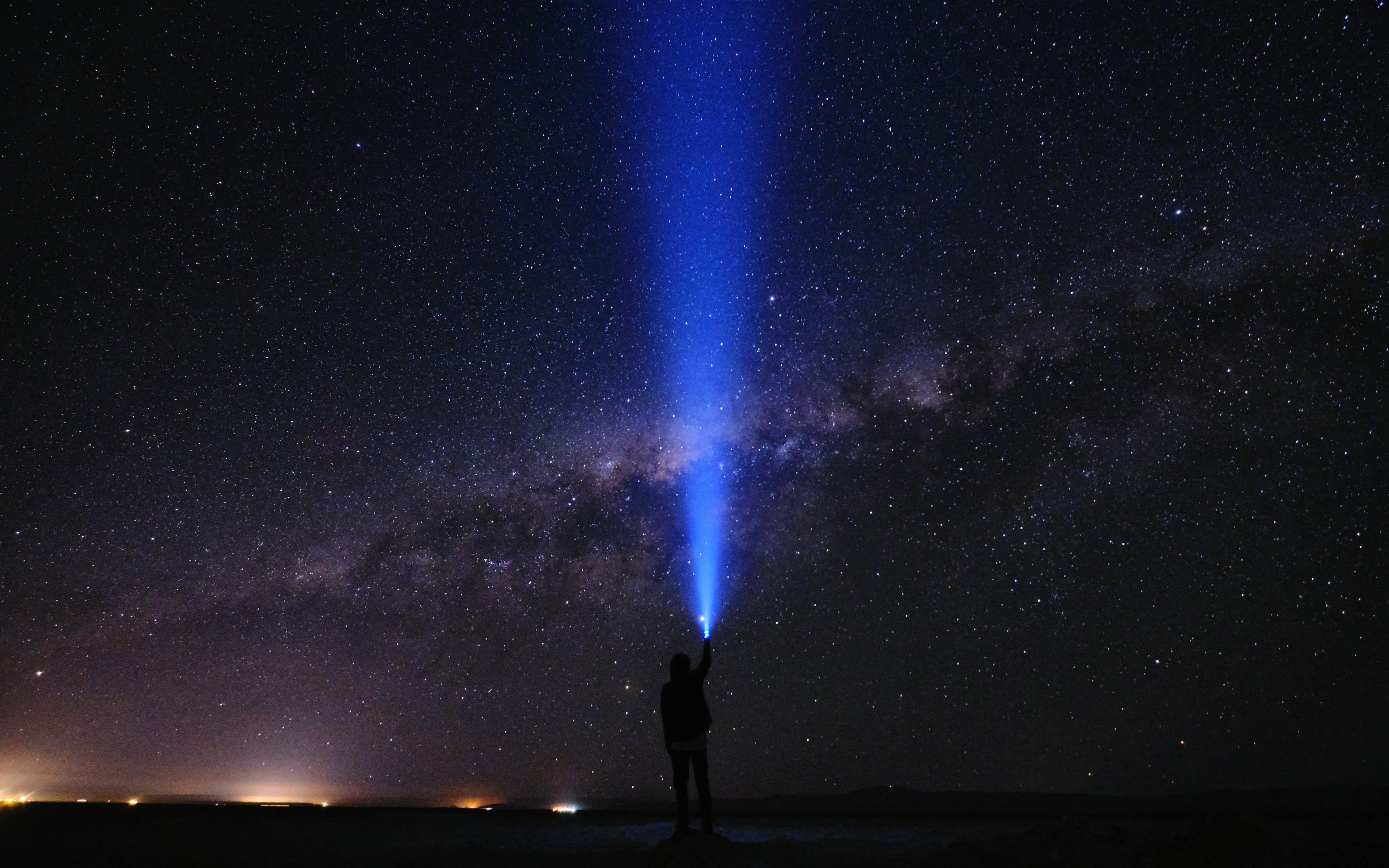 A person silhouetted under the Milky Way in a dark desert sky