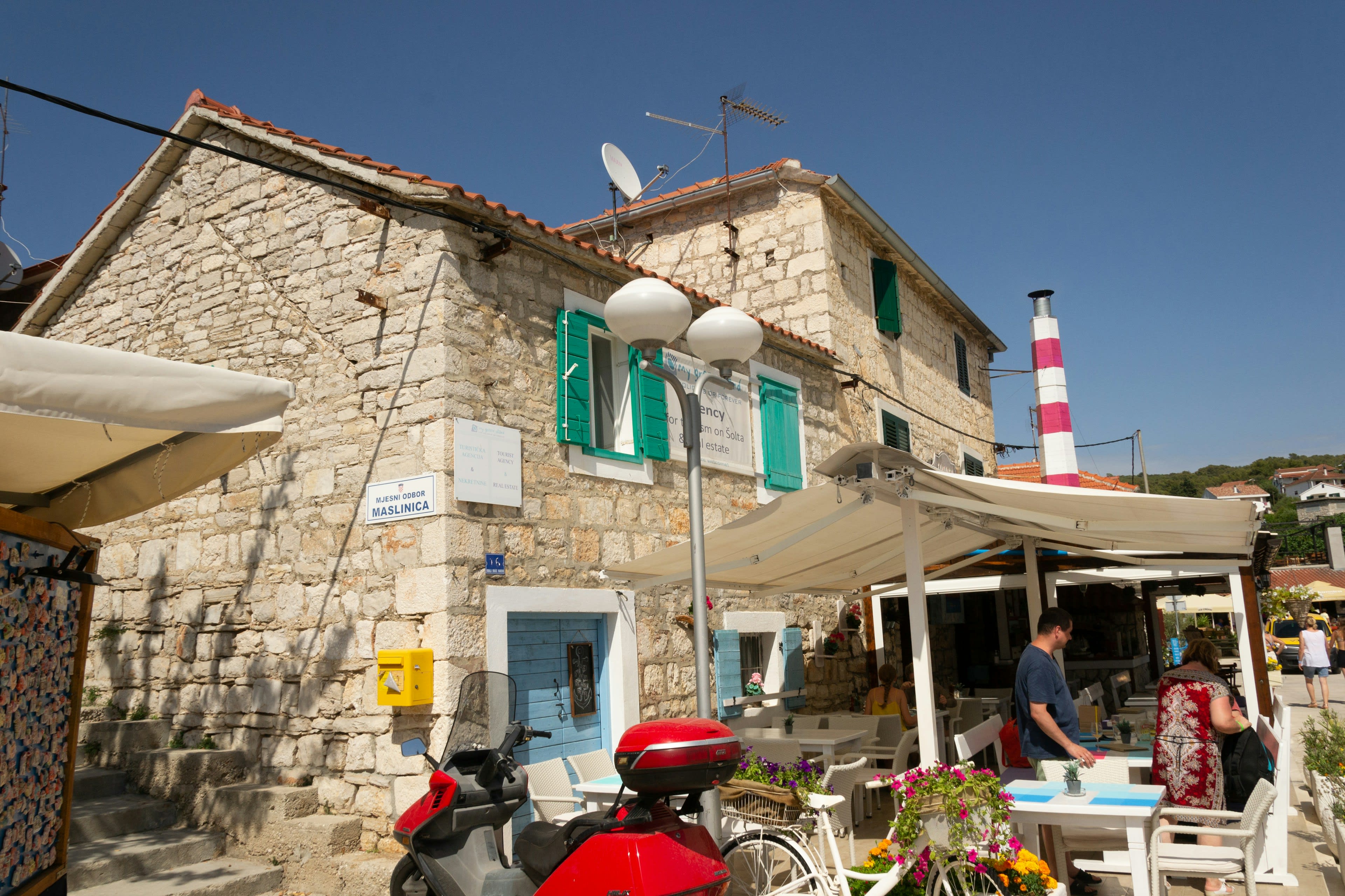 A stone konoba house up a narrow lane with a motorcycle parked outside