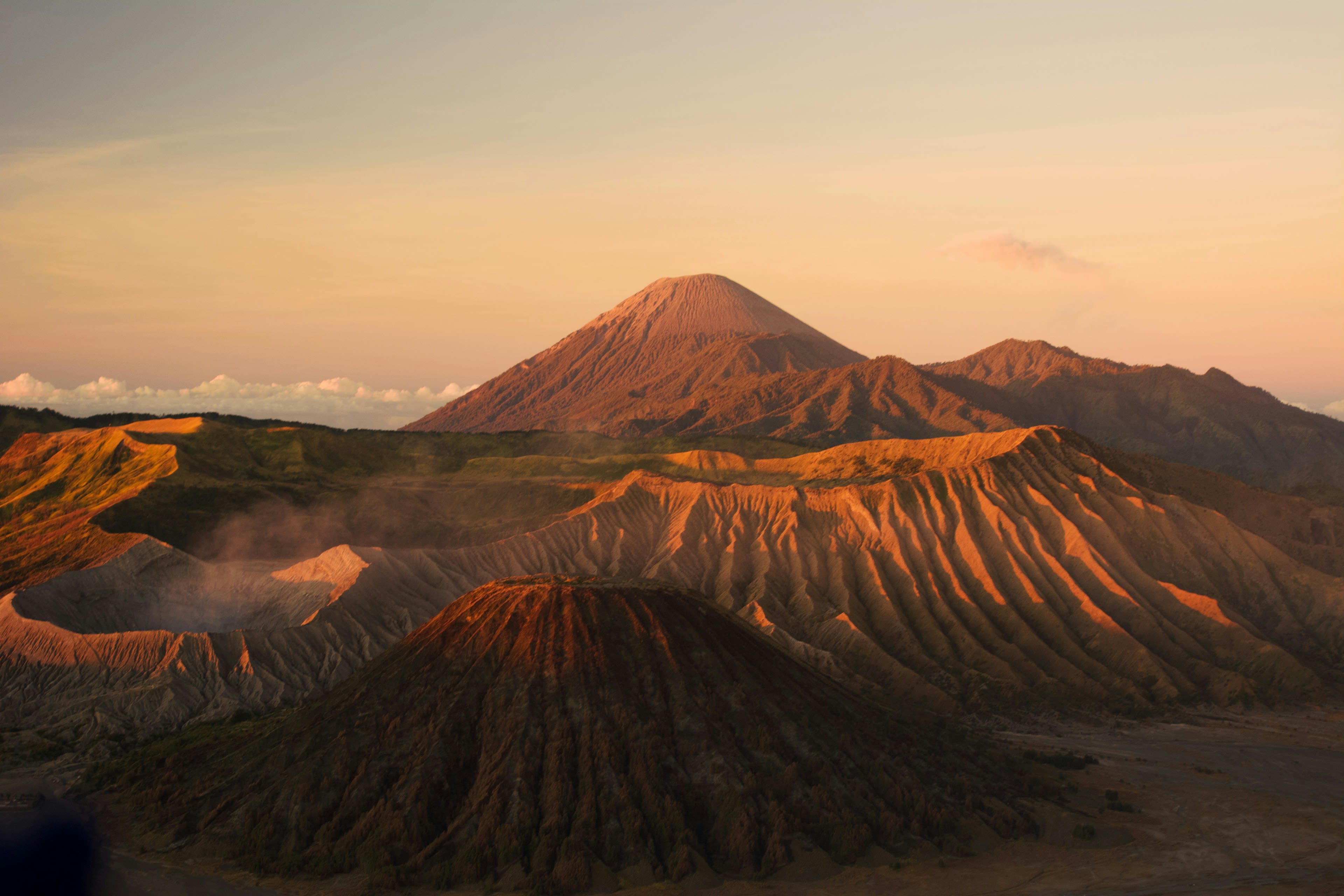 A smoking volcanic cone above a sea of clouds at sunrise