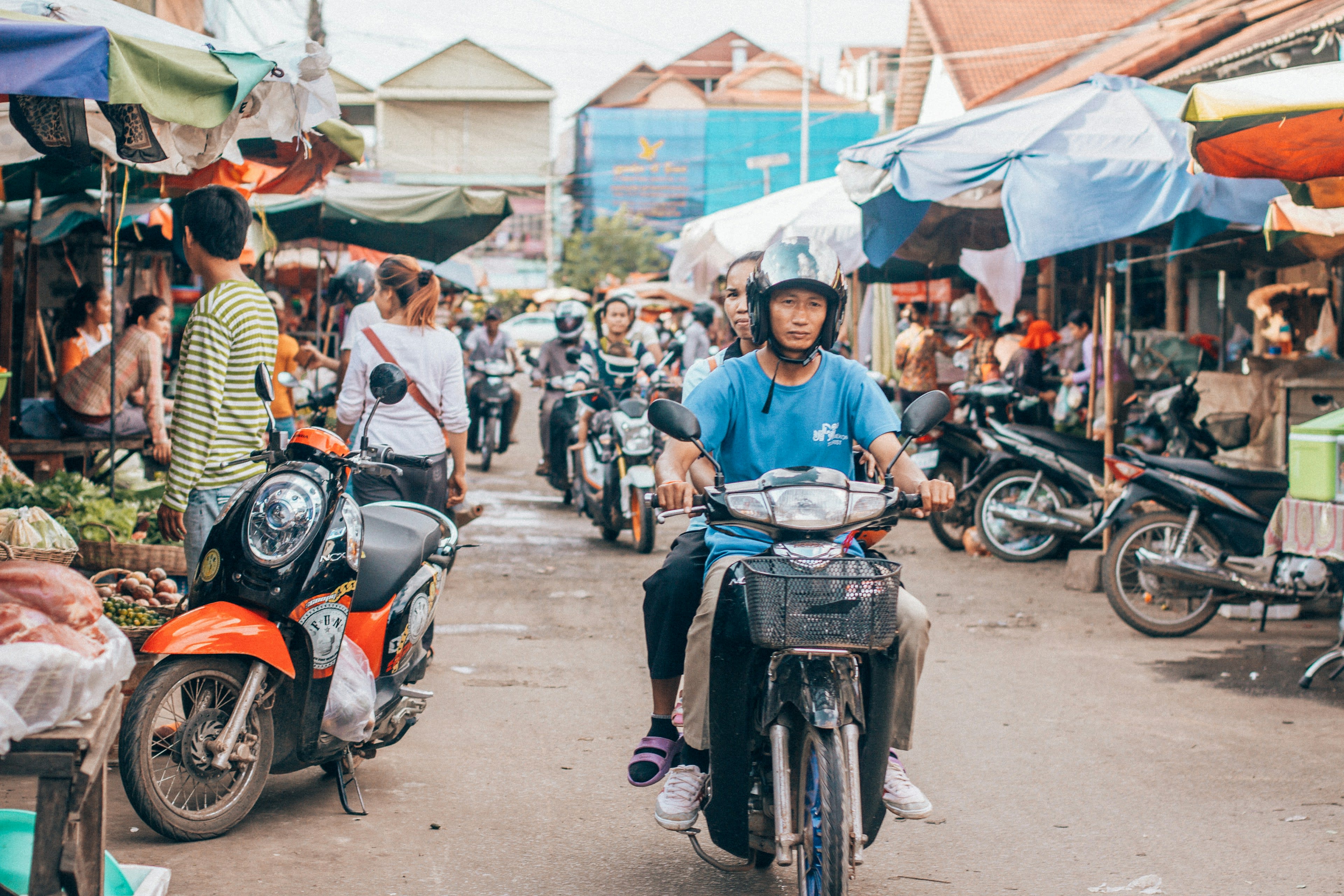A man on a motor scooter moving through a crowded market street