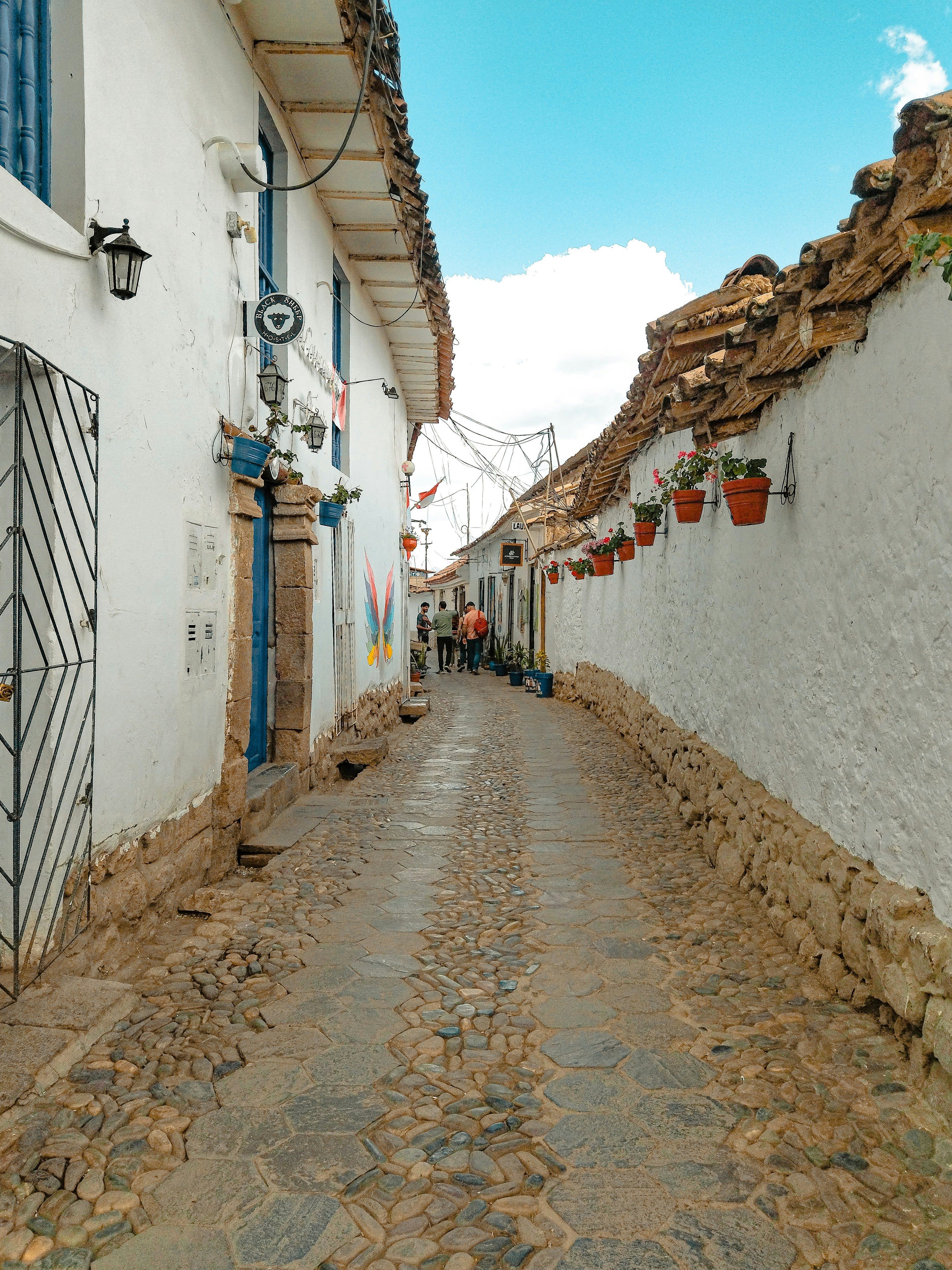A narrow cobbled street in Cusco with whitewashed walls and wooden balconies