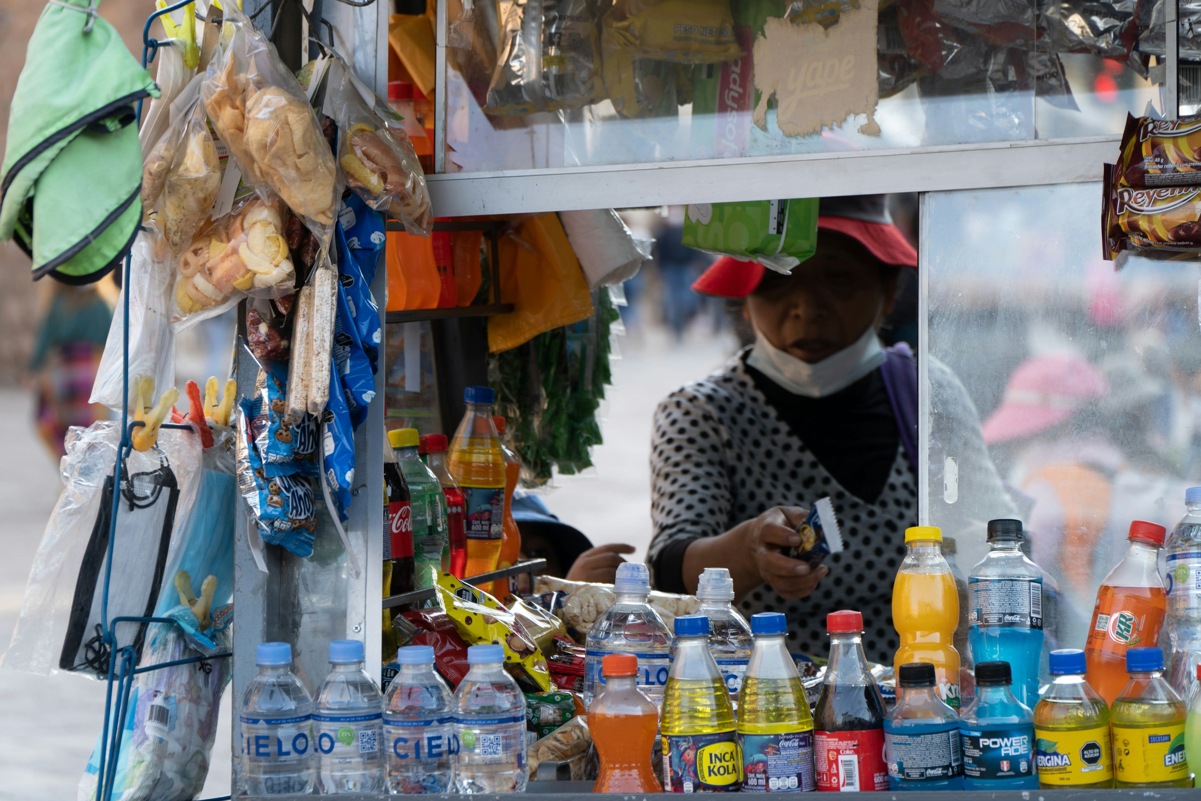 A street vendor stall stacked with bottled drinks and snacks