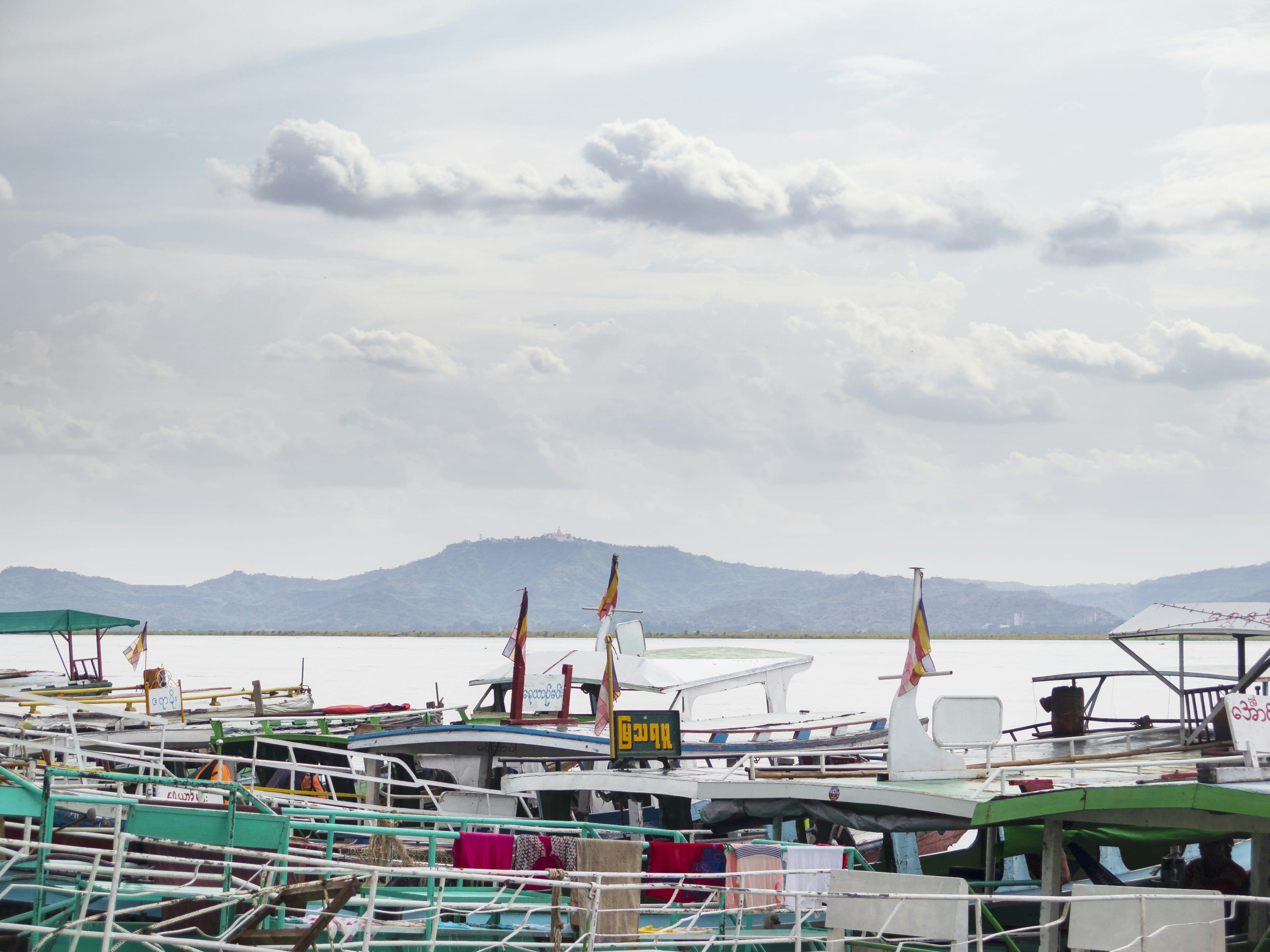 River boats with flags moored at a busy jetty on the Irrawaddy