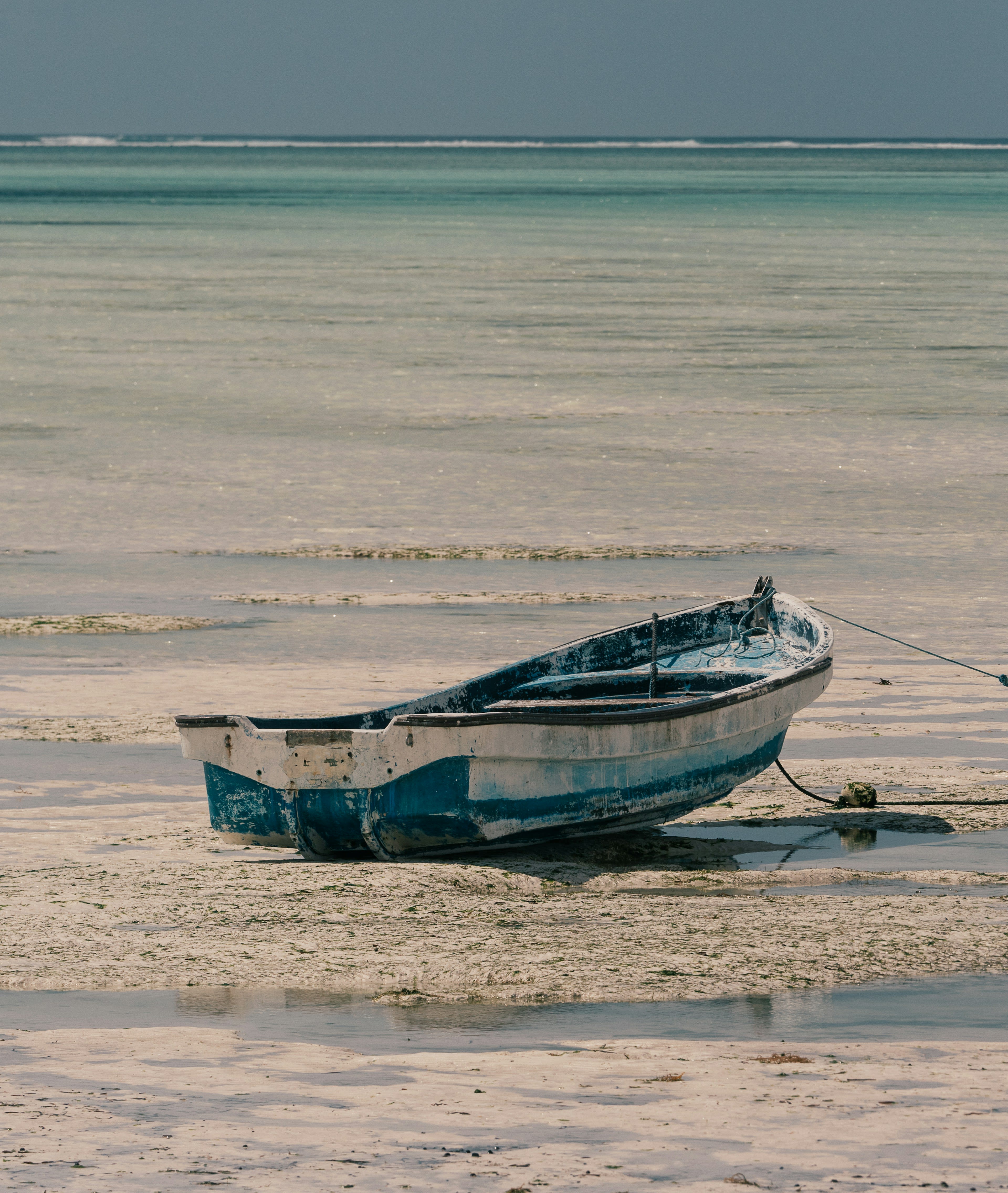 A wooden boat sitting on wet sand at low tide