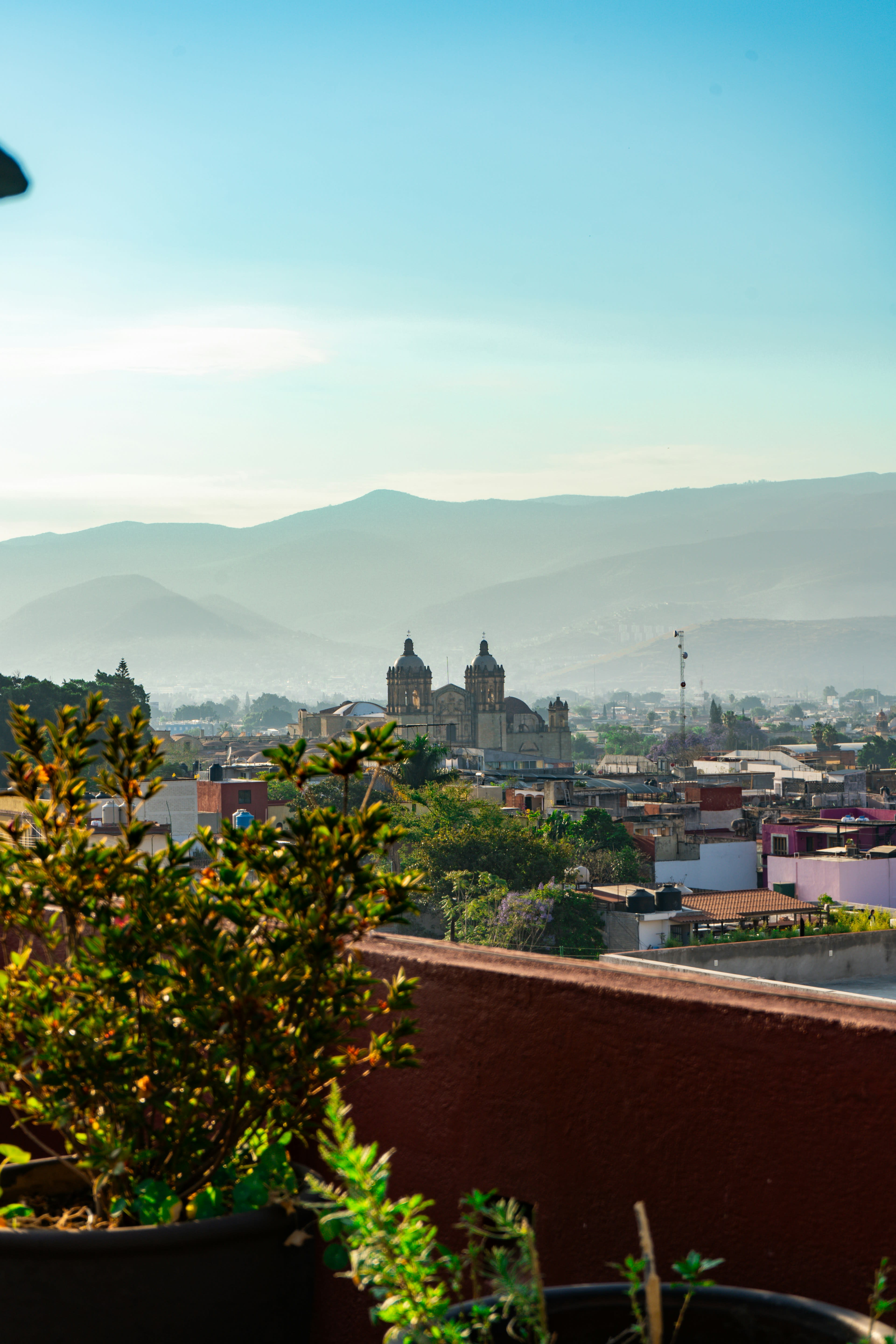 Evening view over Oaxaca rooftops and church domes towards mountains