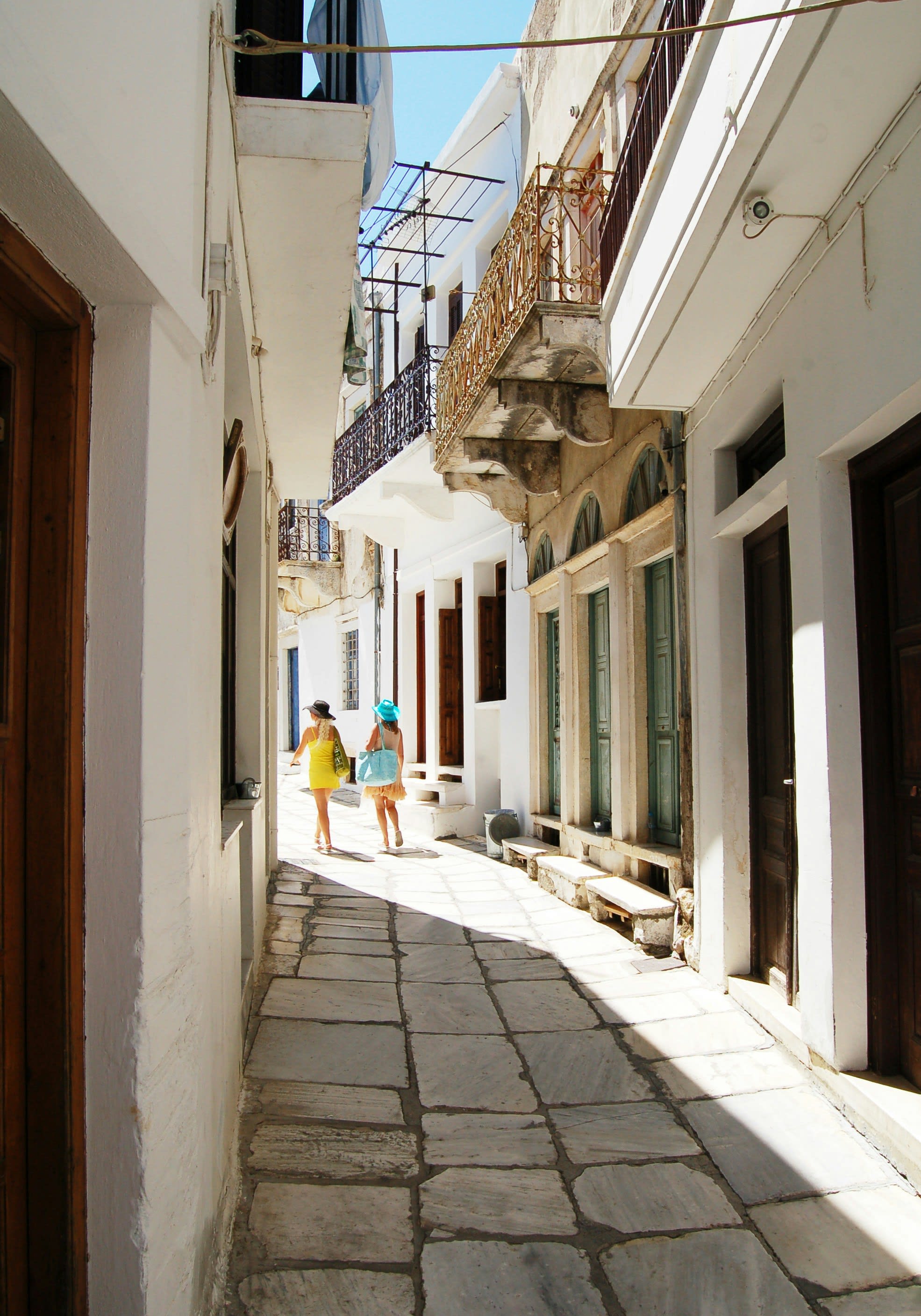 Two women walking between whitewashed buildings in a narrow lane