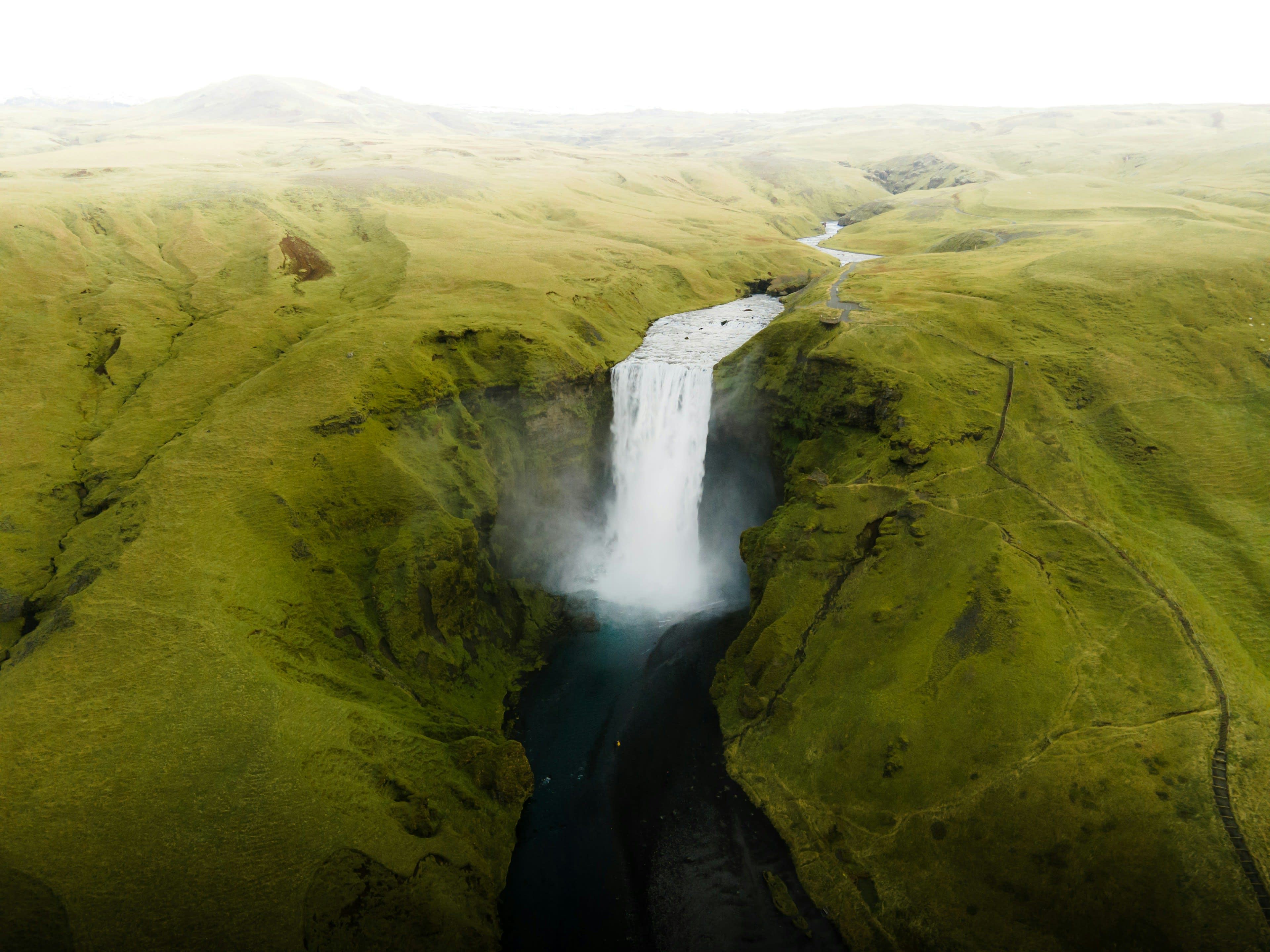 A tall waterfall dropping into a deep gorge, seen from the air