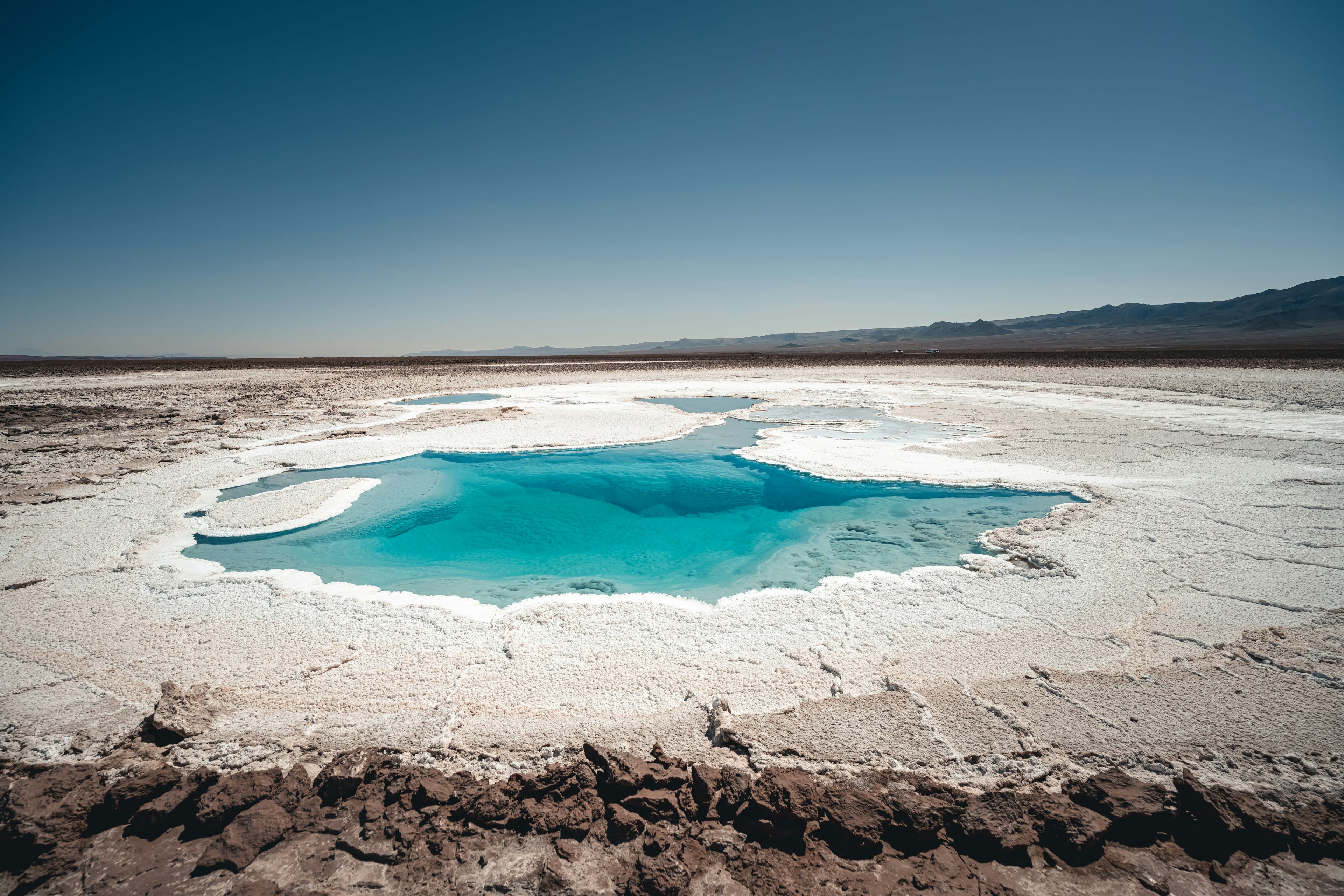 A deep blue lagoon set in white salt crust in the Atacama desert