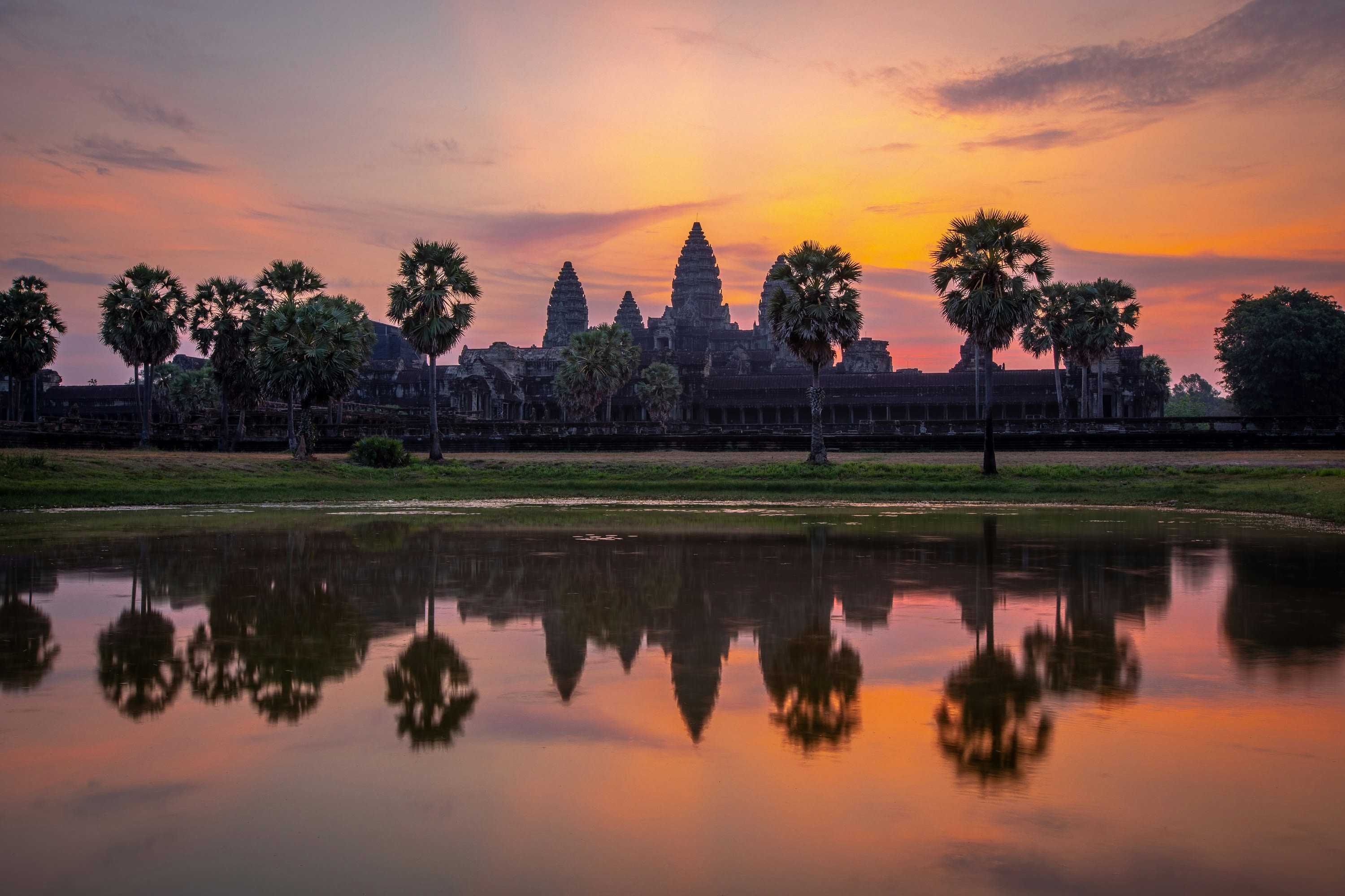 Angkor Wat's towers silhouetted at sunrise and reflected in a pond