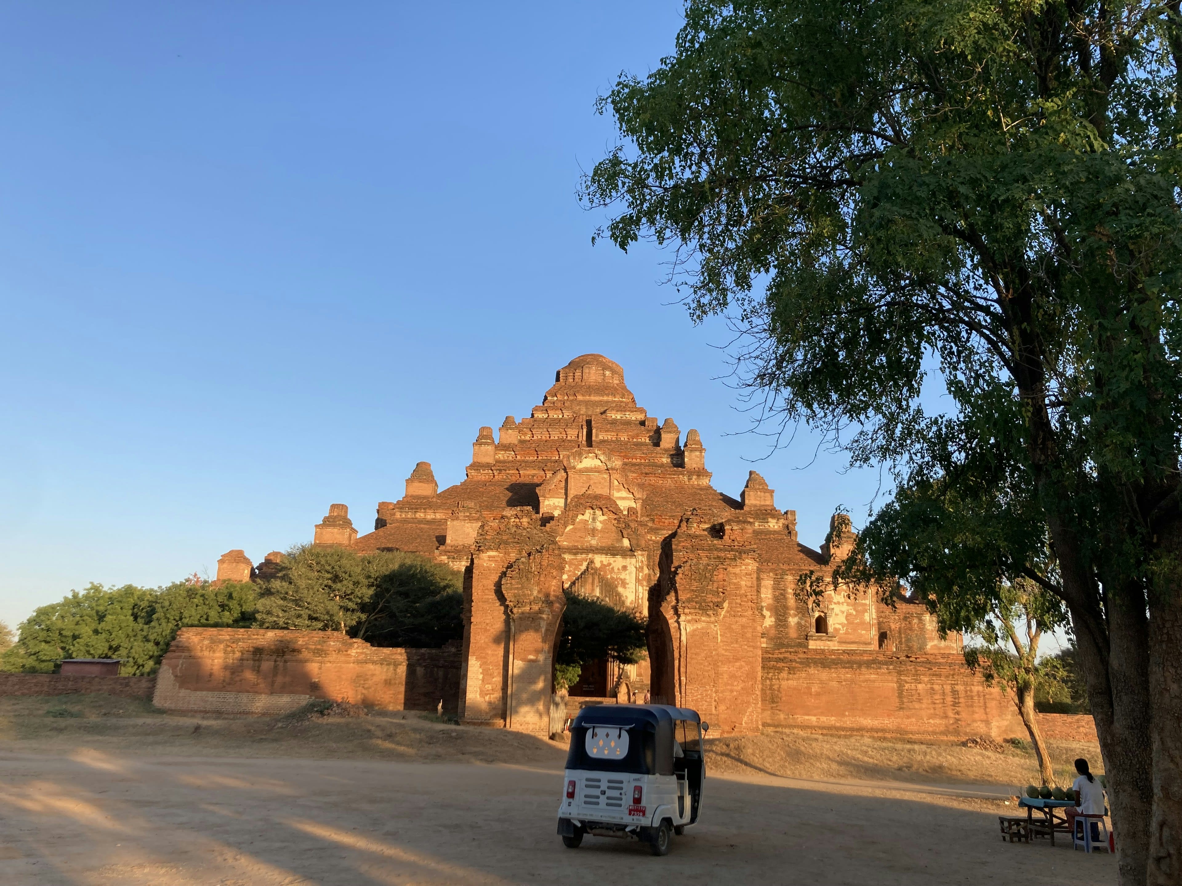 A small electric cart parked in front of a large brick temple in Bagan