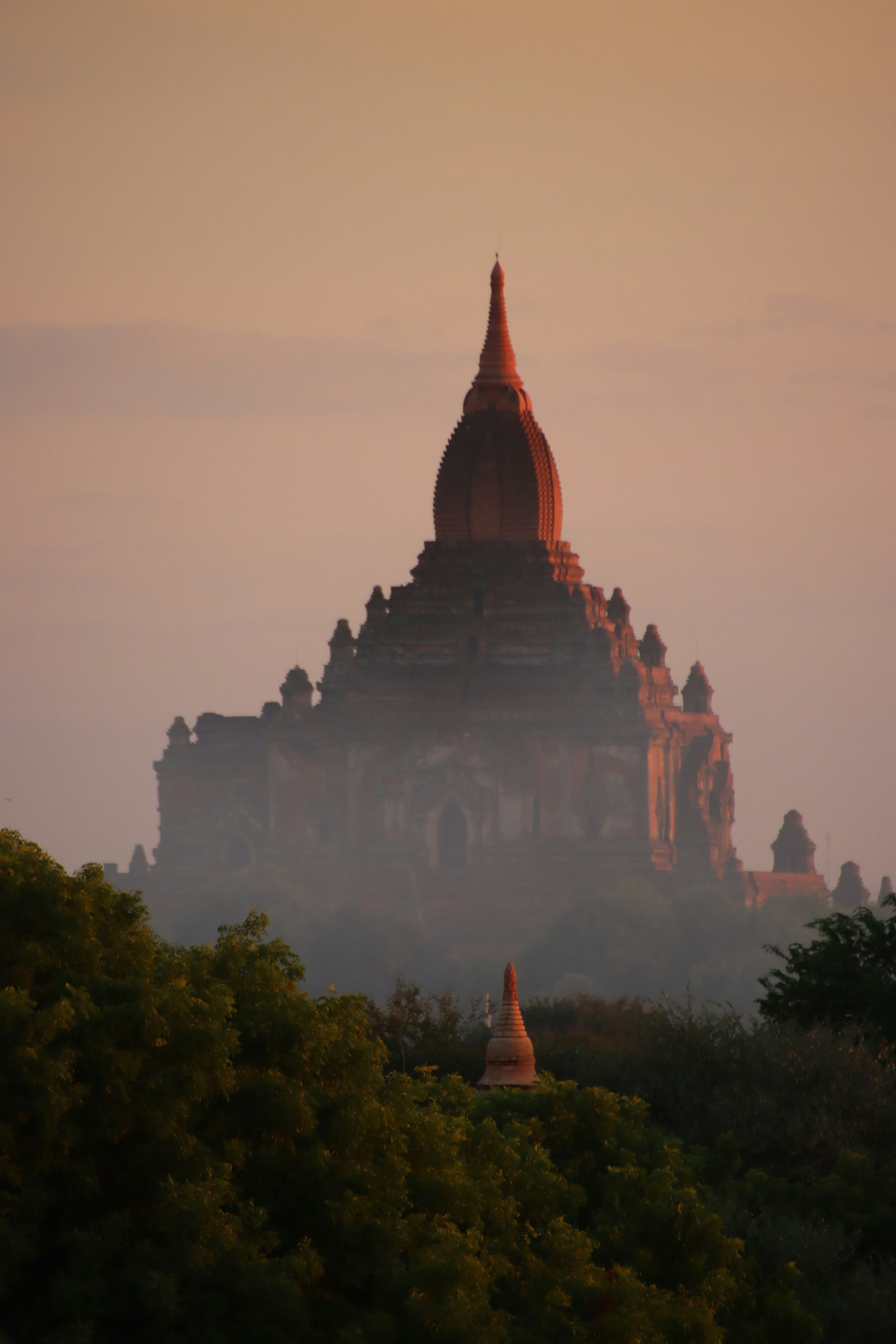 A single temple spire silhouetted in golden morning mist