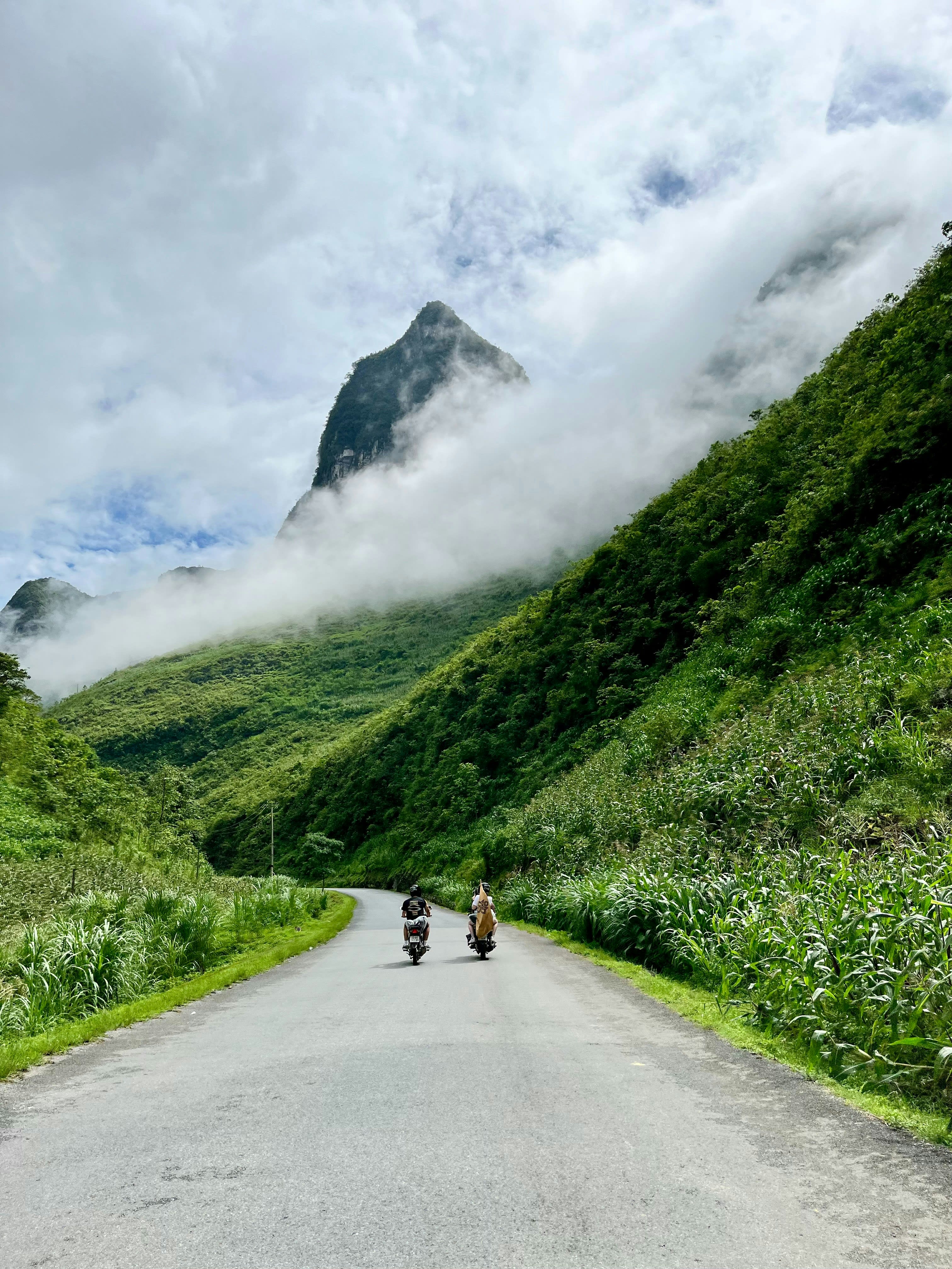 Motorbike riders on a mountain road beneath a limestone peak