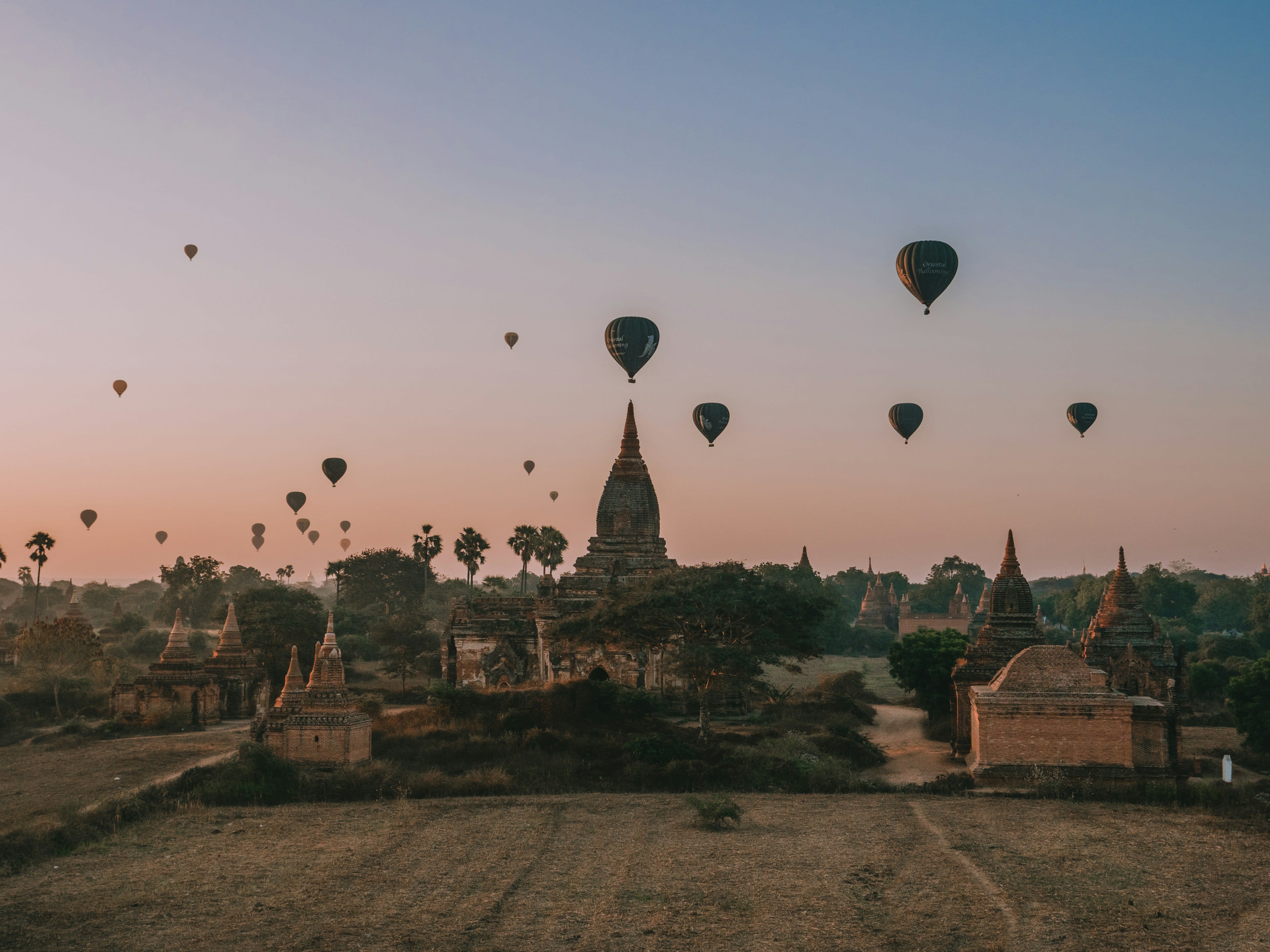 Hot air balloons drifting over temple spires in dawn mist at Bagan