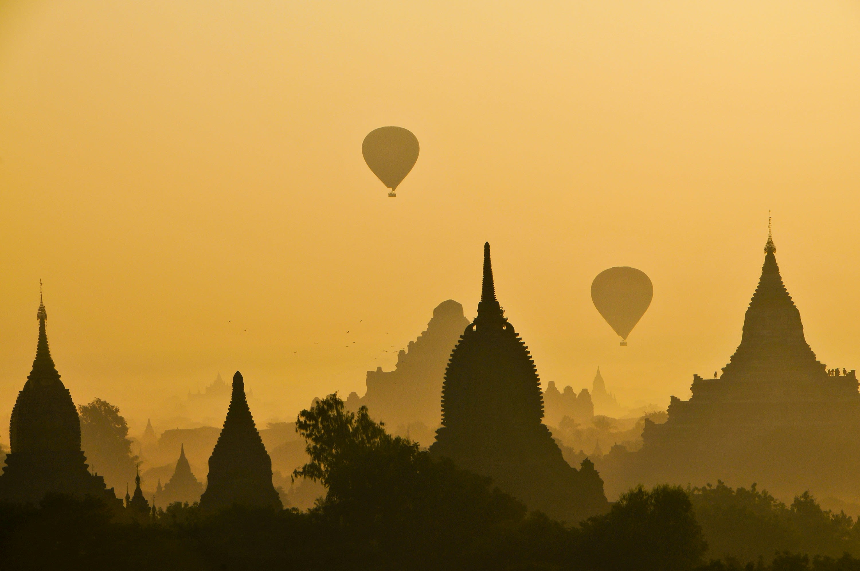 Temple silhouettes and two hot air balloons in golden evening haze
