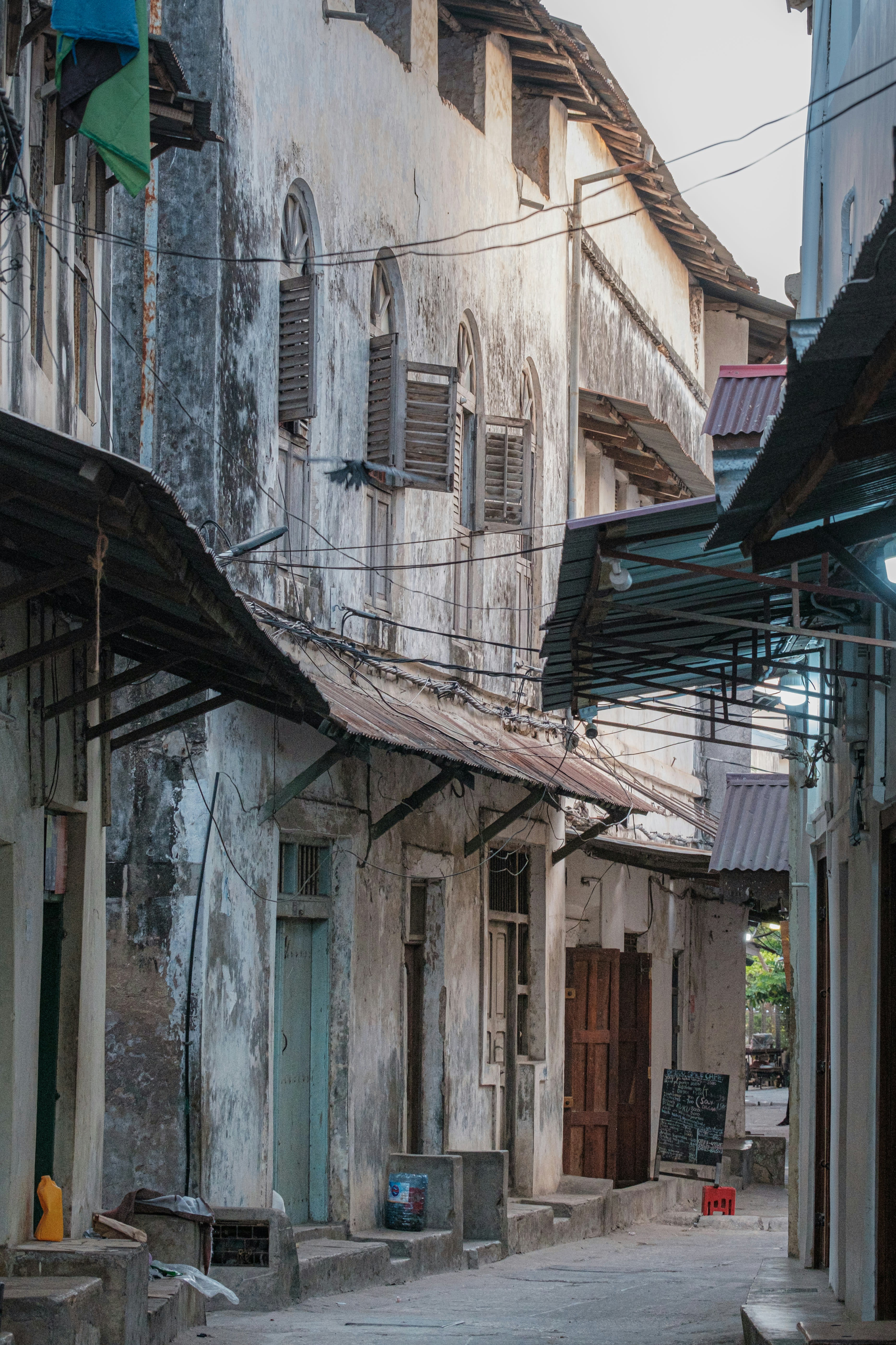 A narrow alley between weathered coral-stone buildings in Stone Town