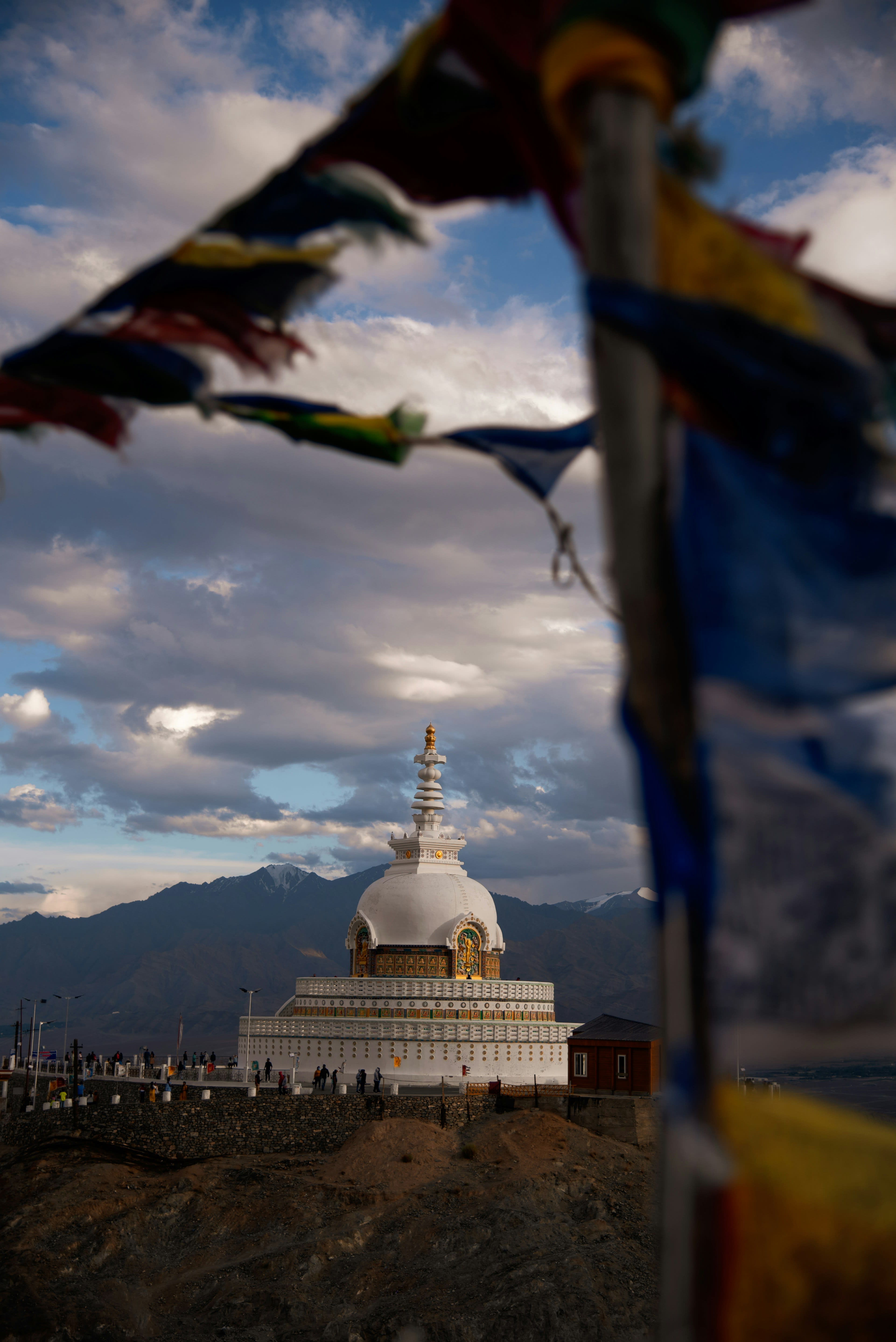 A white stupa framed by strings of prayer flags against a dusk sky
