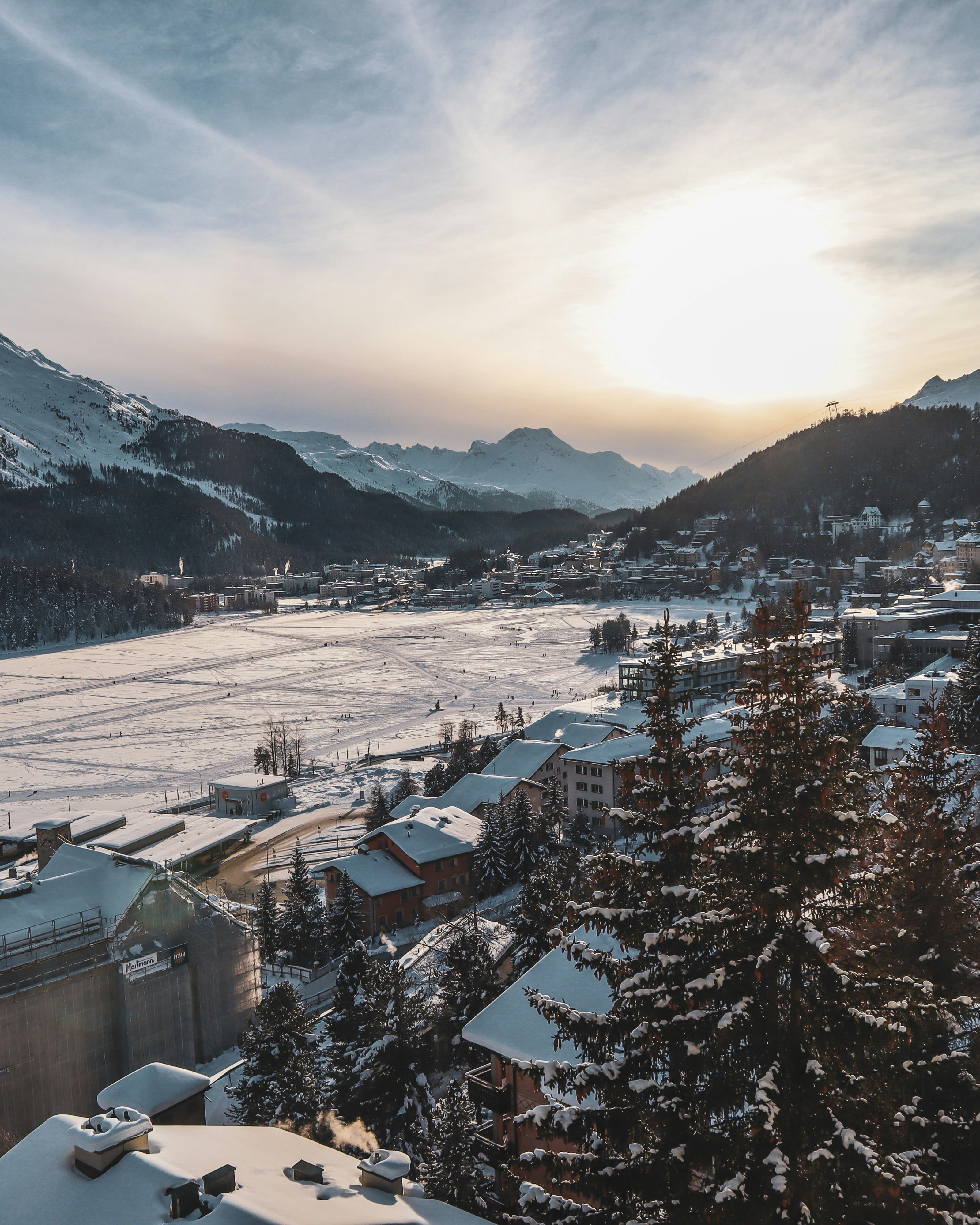 A snowy alpine town at dusk with sun low over the mountains