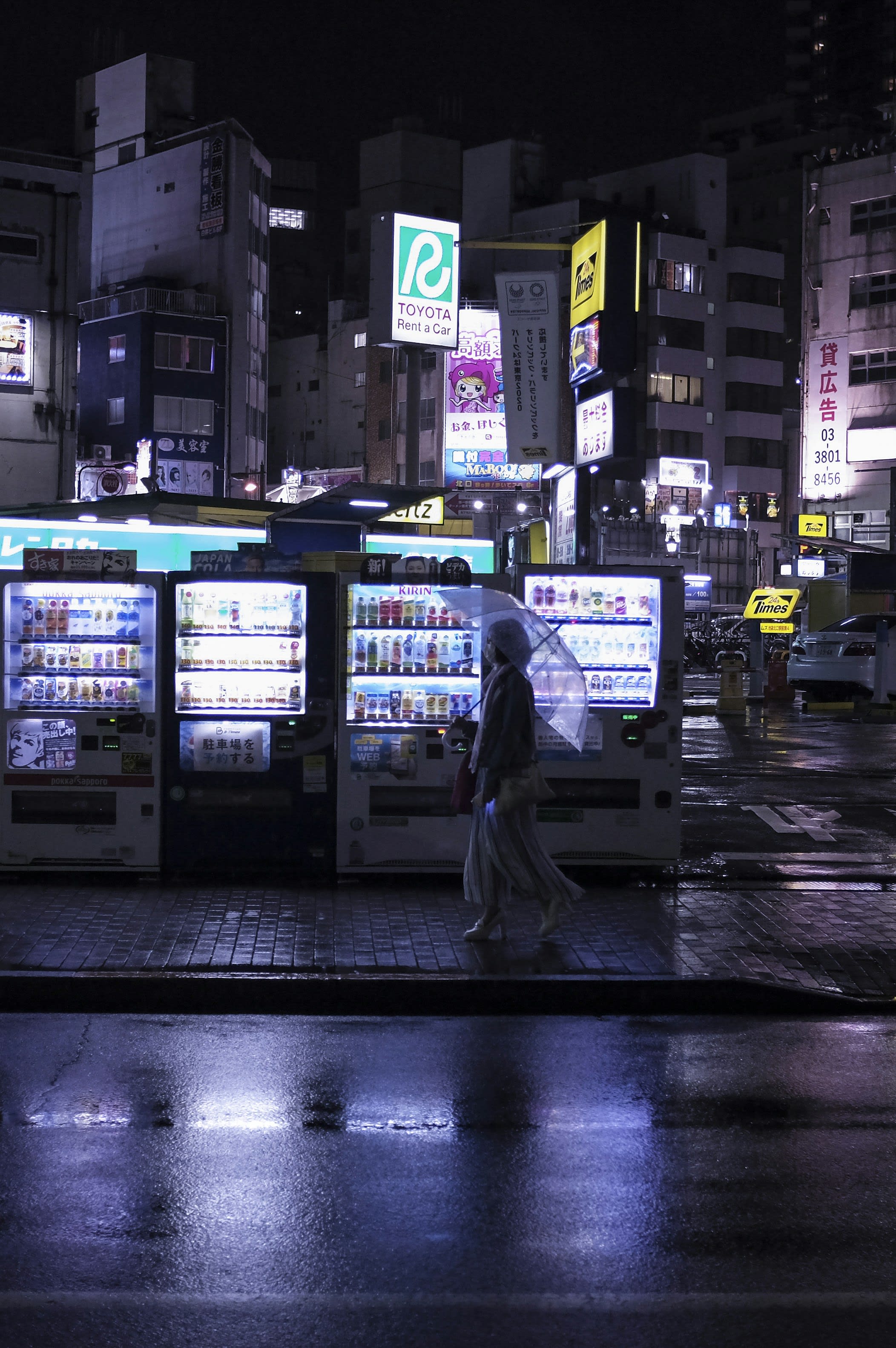 Two brightly lit vending machines glowing on a dark residential street at night