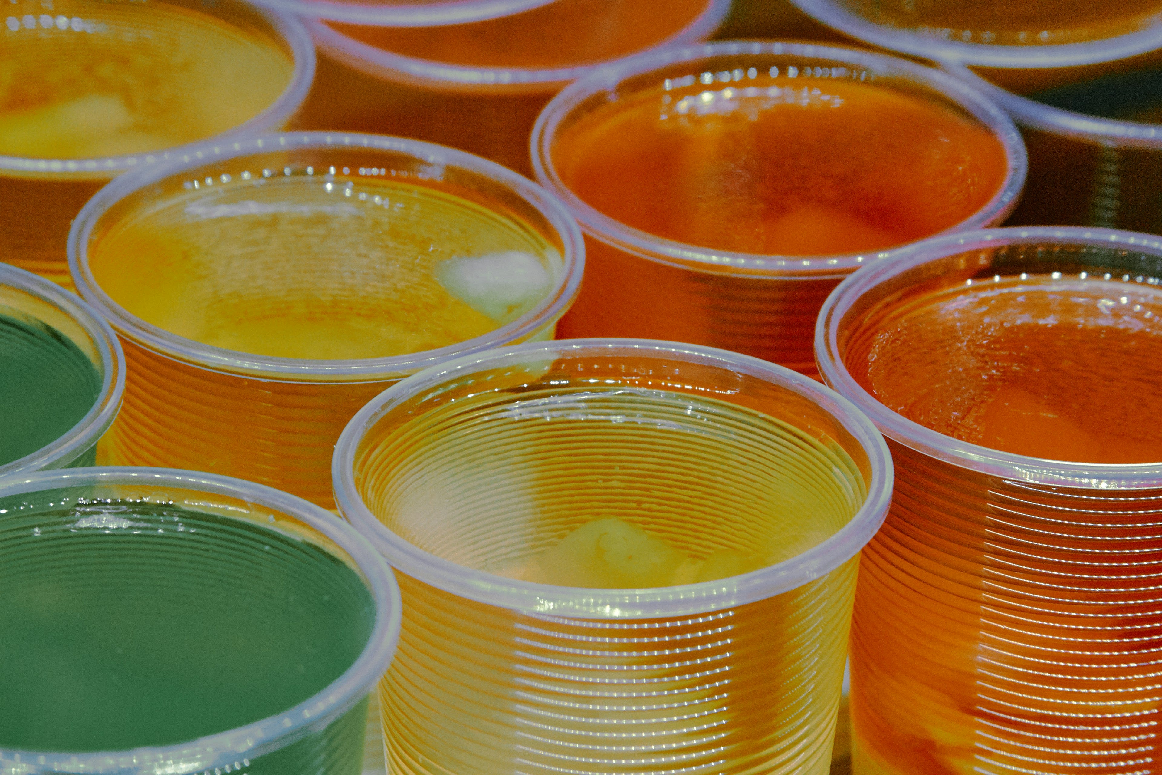 Glass jars of orange and yellow aguas frescas on a market counter