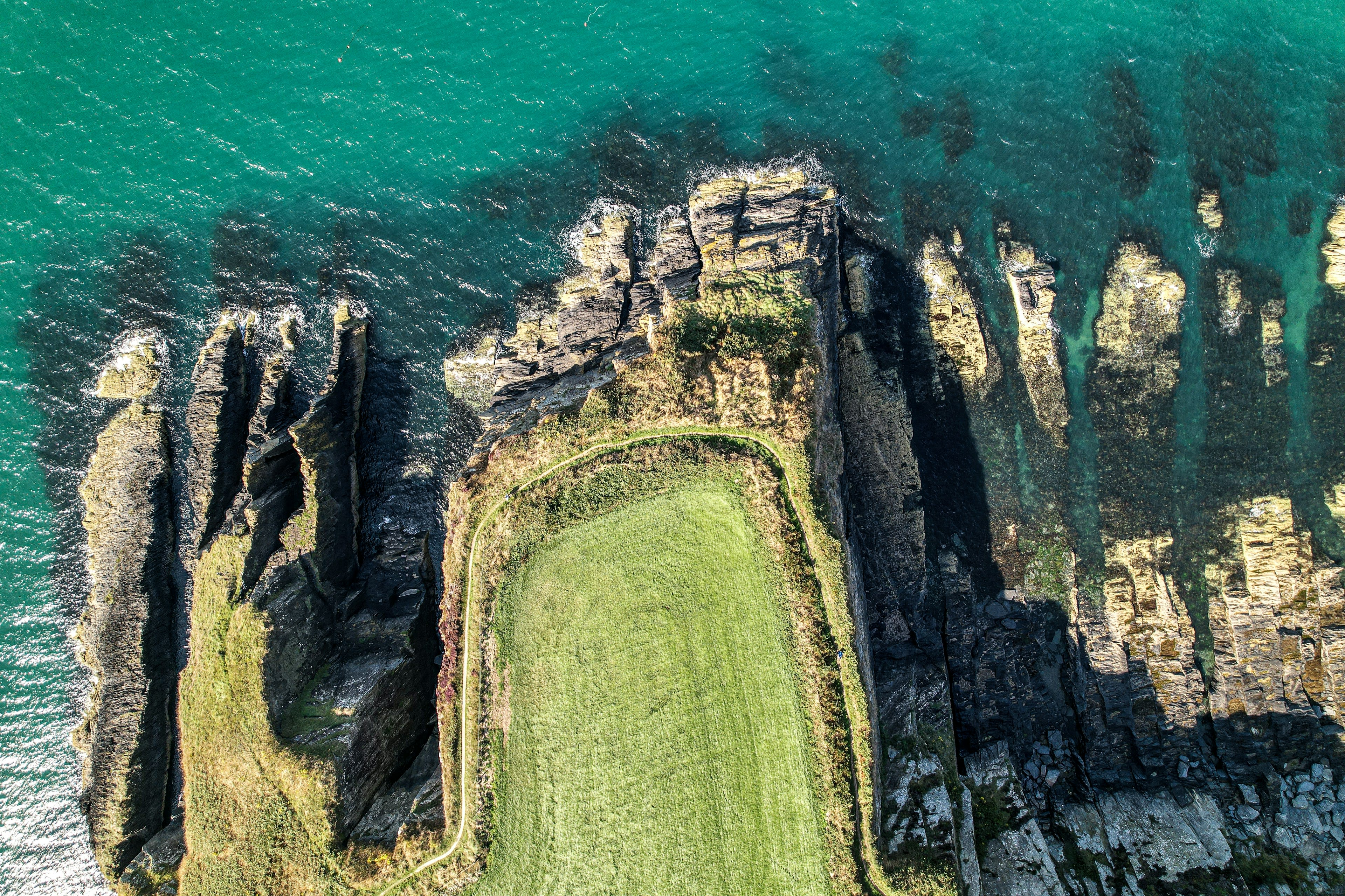 Aerial view of jagged dark rock ledges running into white Atlantic surf