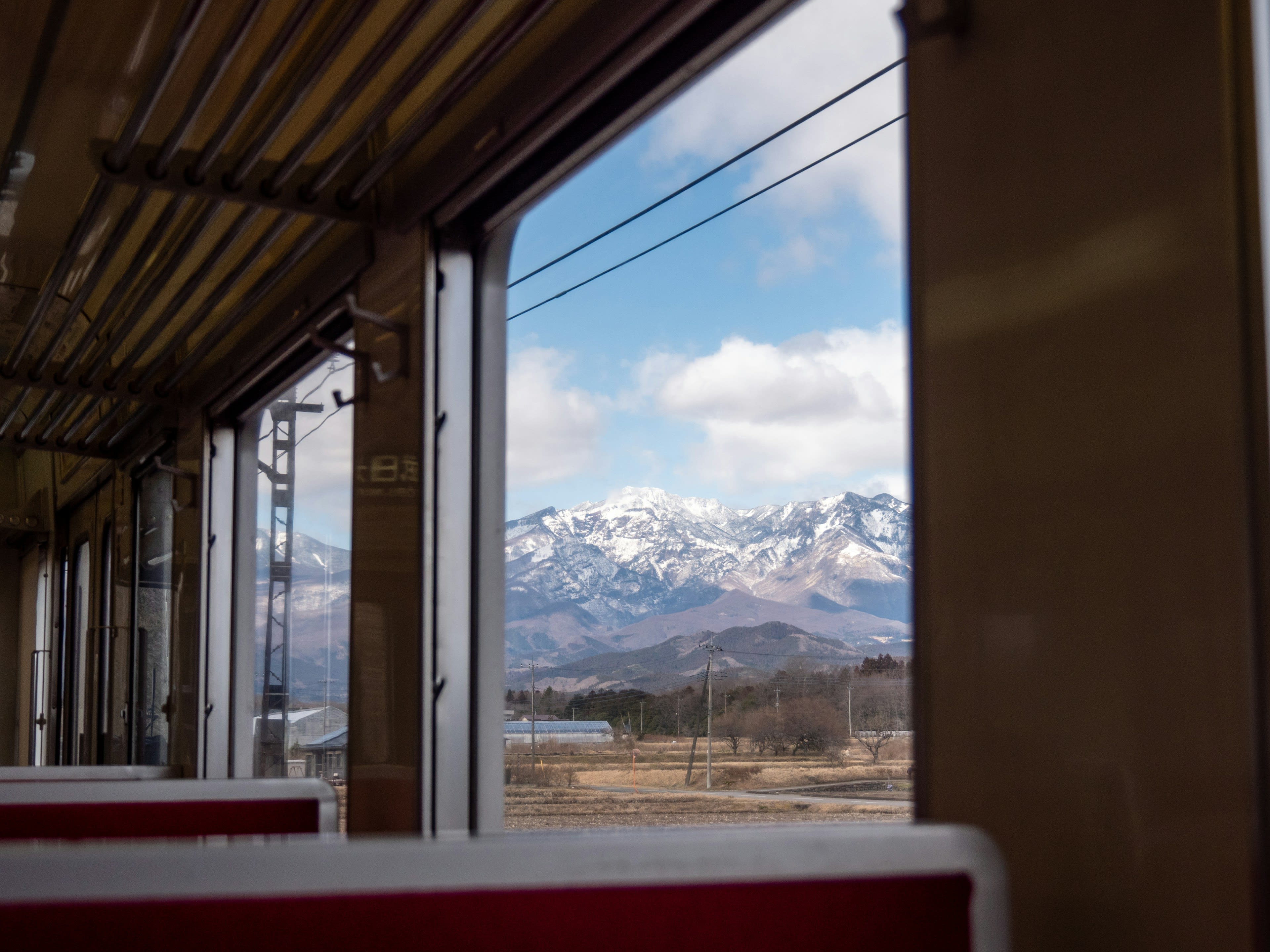 The interior of a small local train with snow-covered mountains through the window