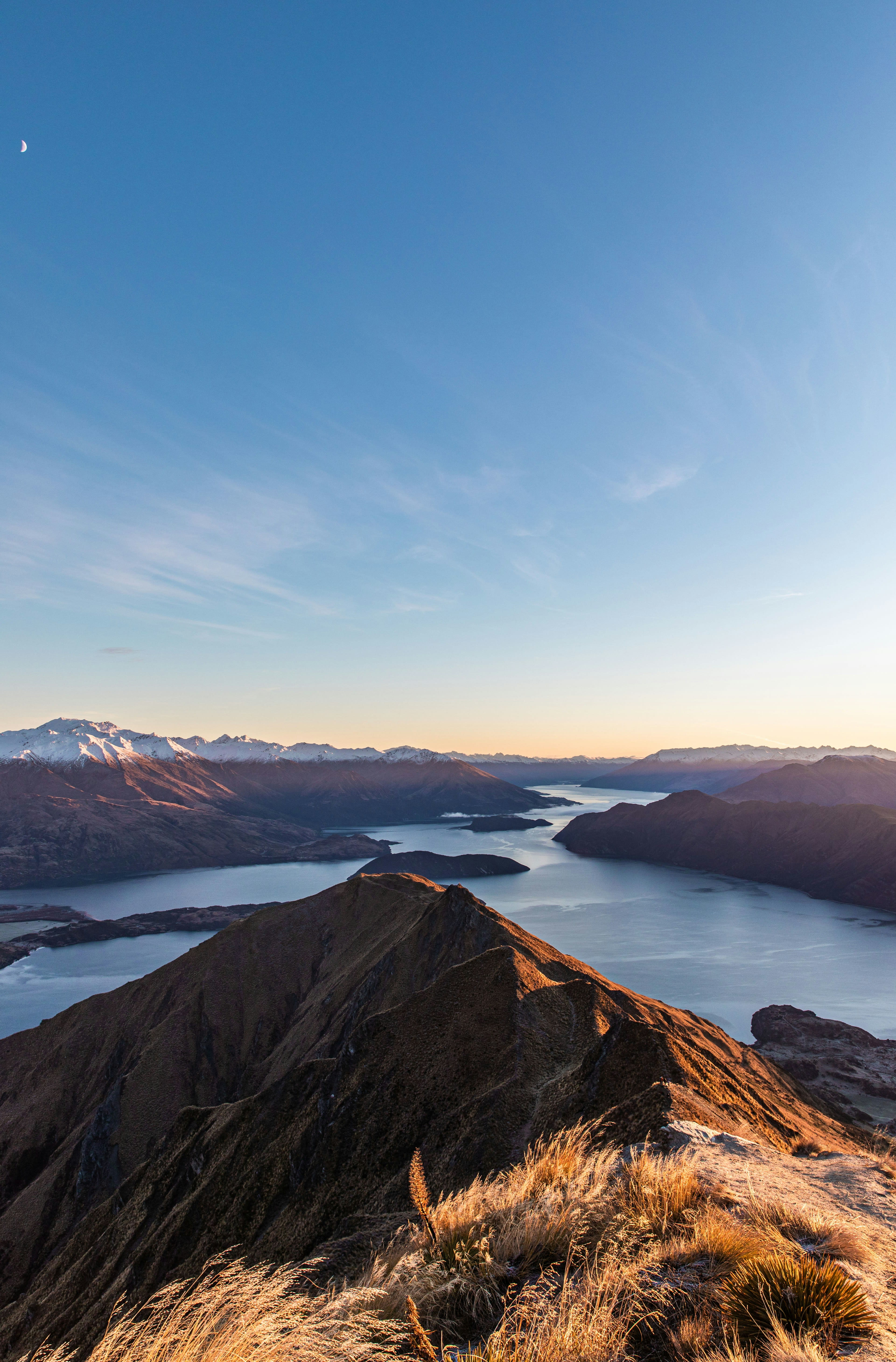 Golden evening light over ridgelines and a lake seen from a peak