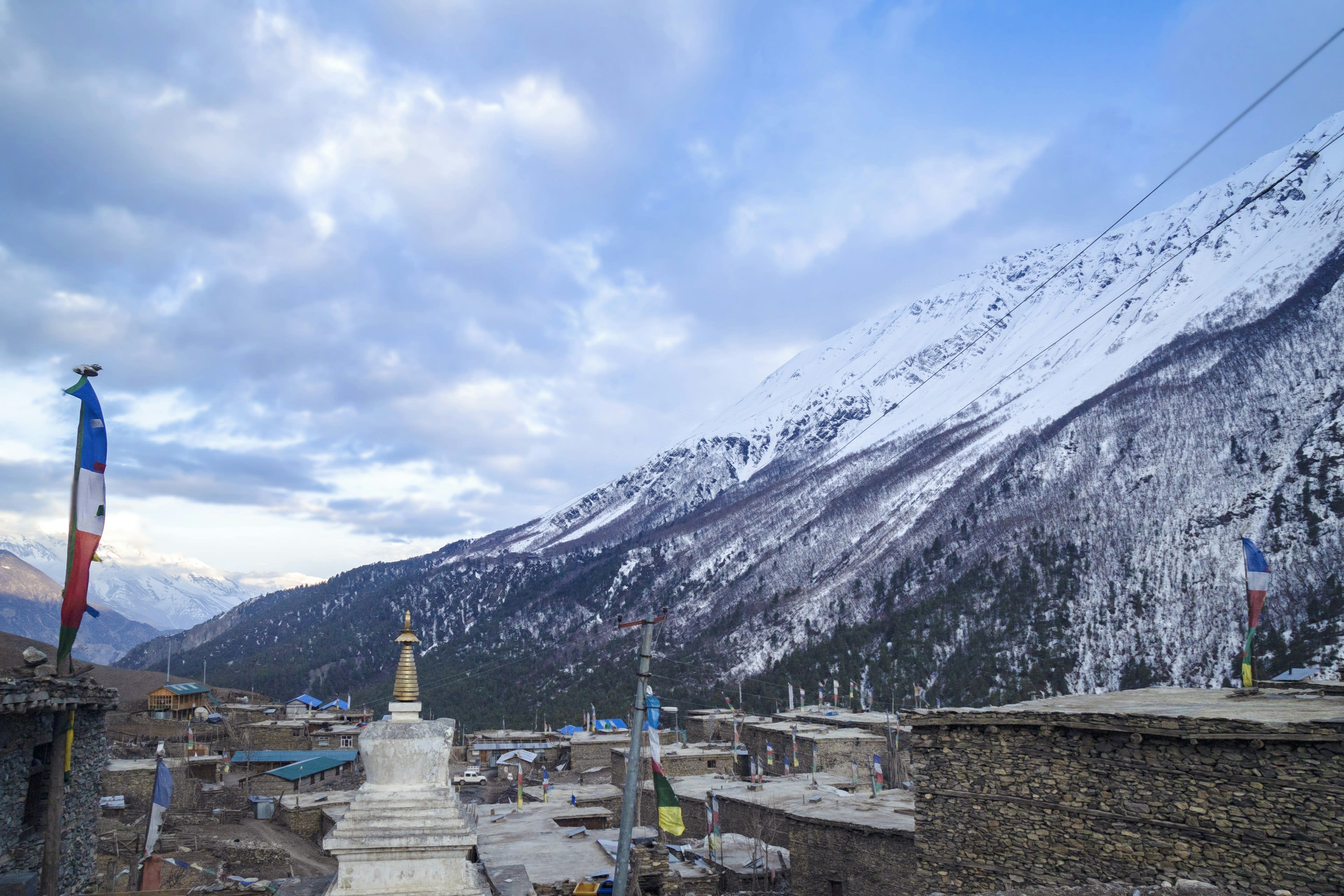 A stone village with stupas below snow-covered Himalayan peaks