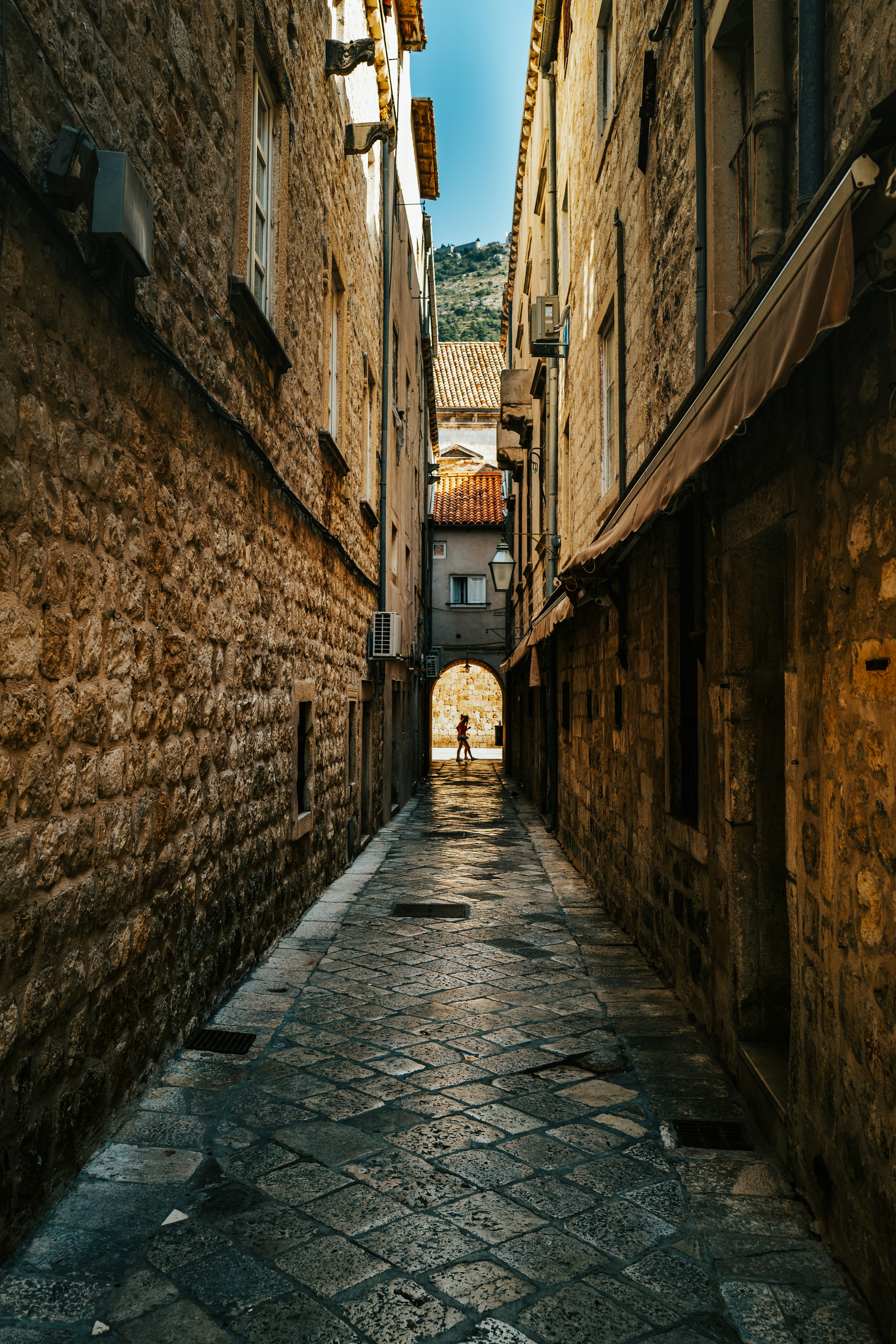A narrow stone alley in Dubrovnik with weathered walls