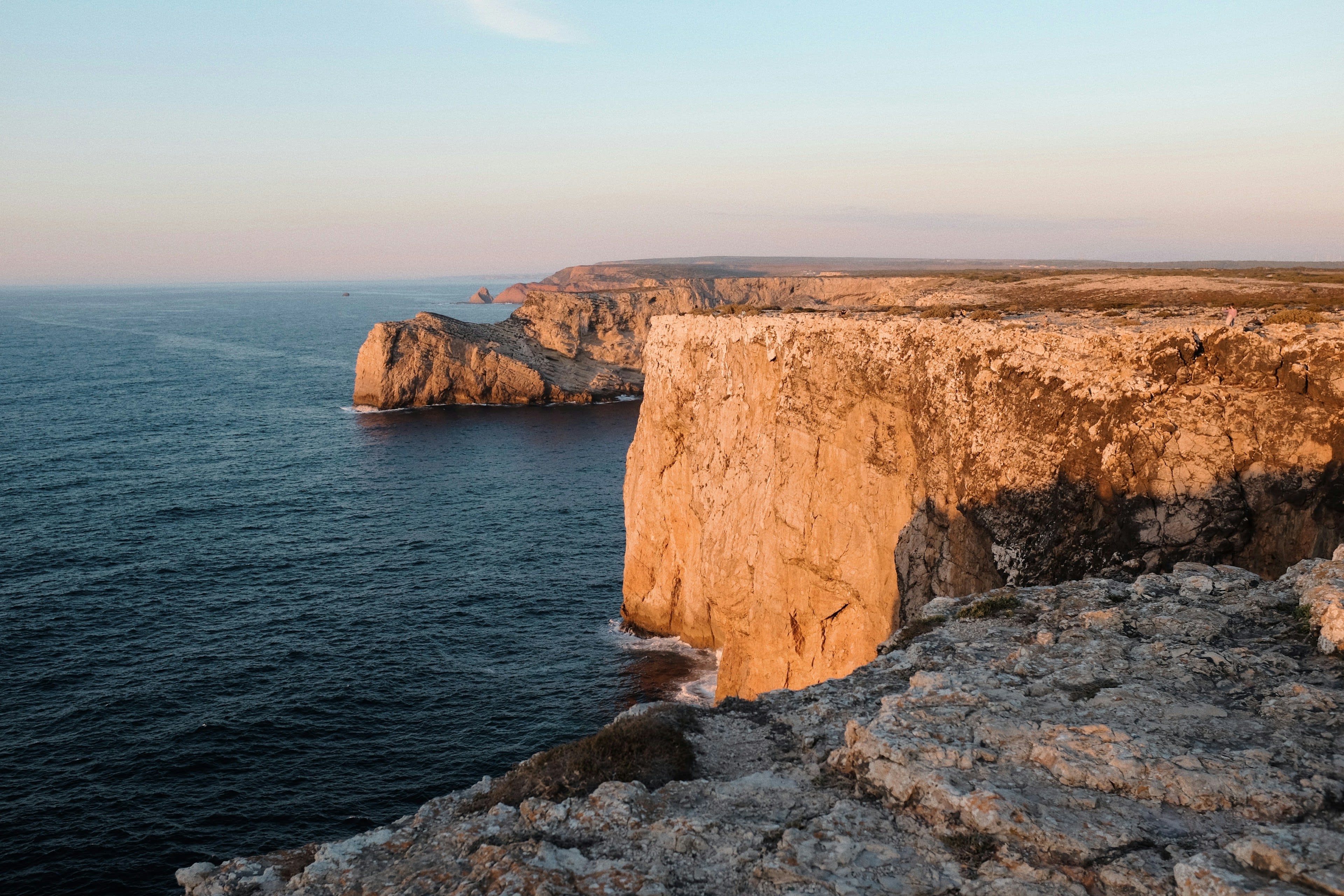 Golden evening light on high sea cliffs above dark water