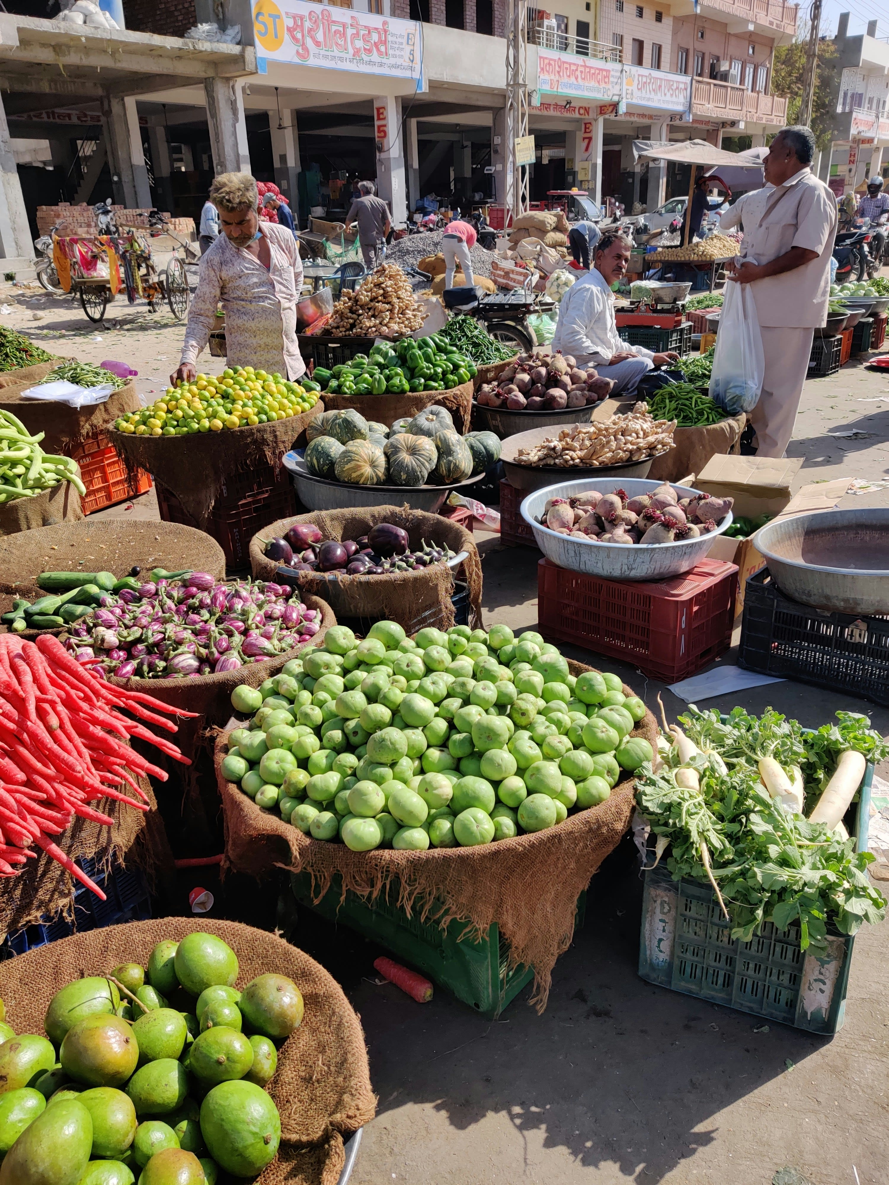 A vendor at a market stall stacked with fresh vegetables