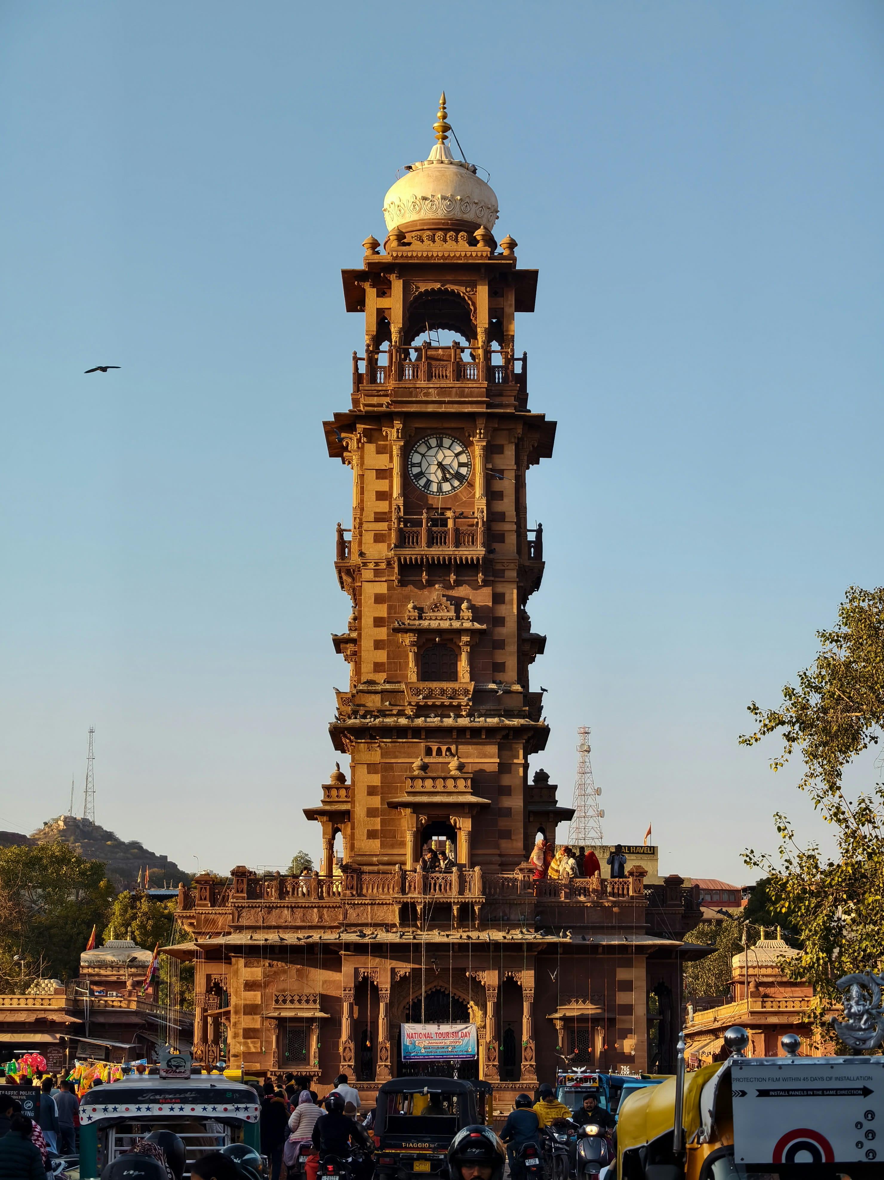 A sandstone clock tower rising over a busy market square
