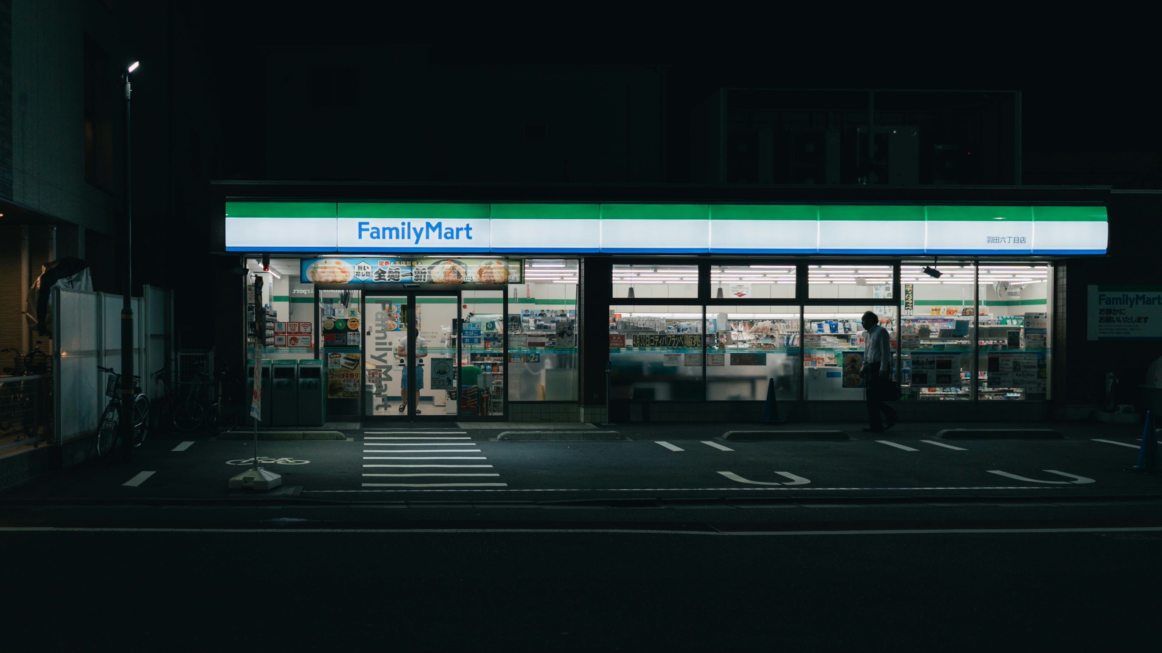 A lit convenience store at night on an empty street corner