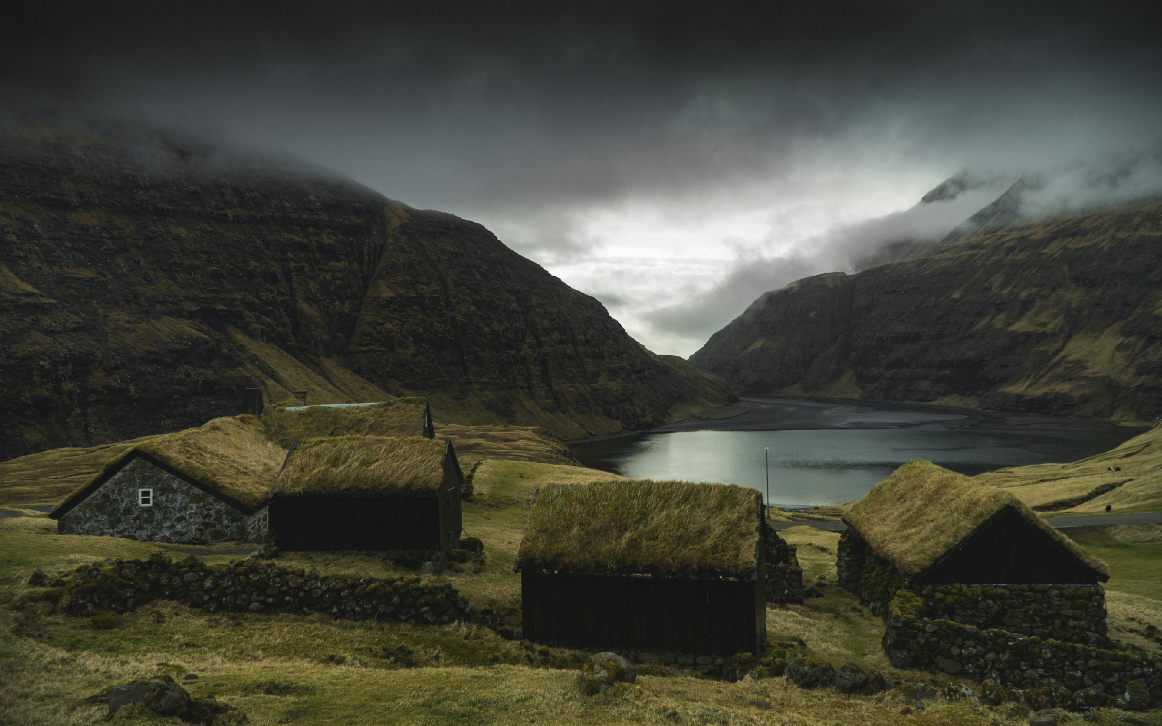 Turf-roofed black houses beside a tidal lagoon under low cloud