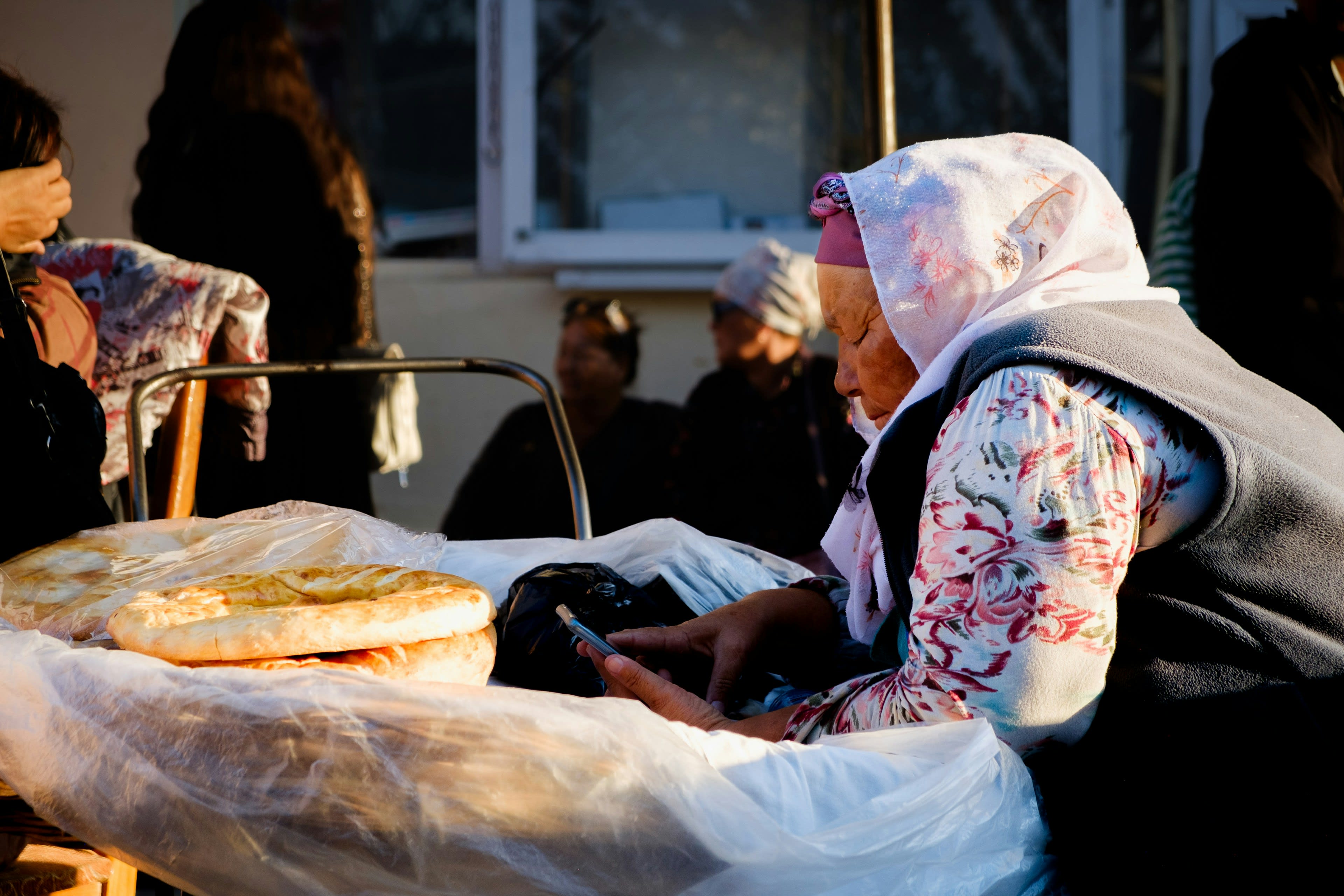 A bread seller seated behind stacked round loaves at a bazaar