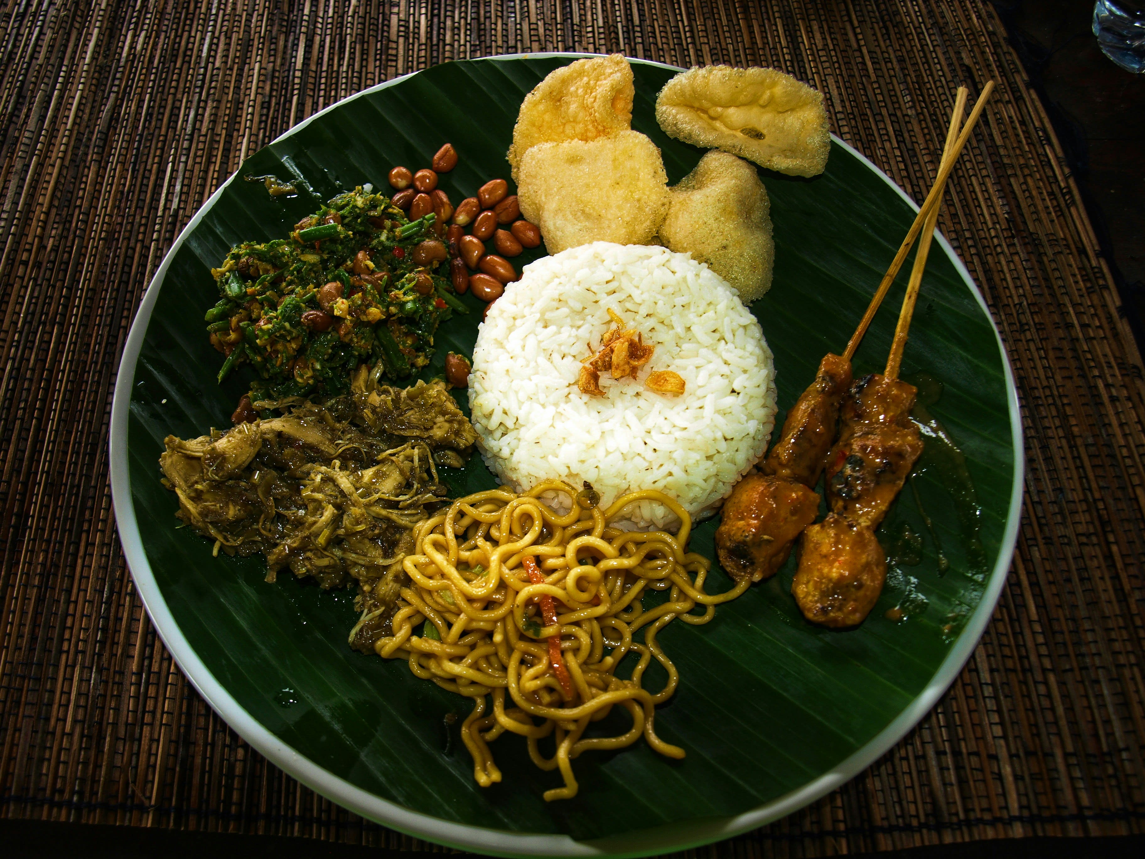 A banana-leaf plate of rice with satay, vegetables and sambal