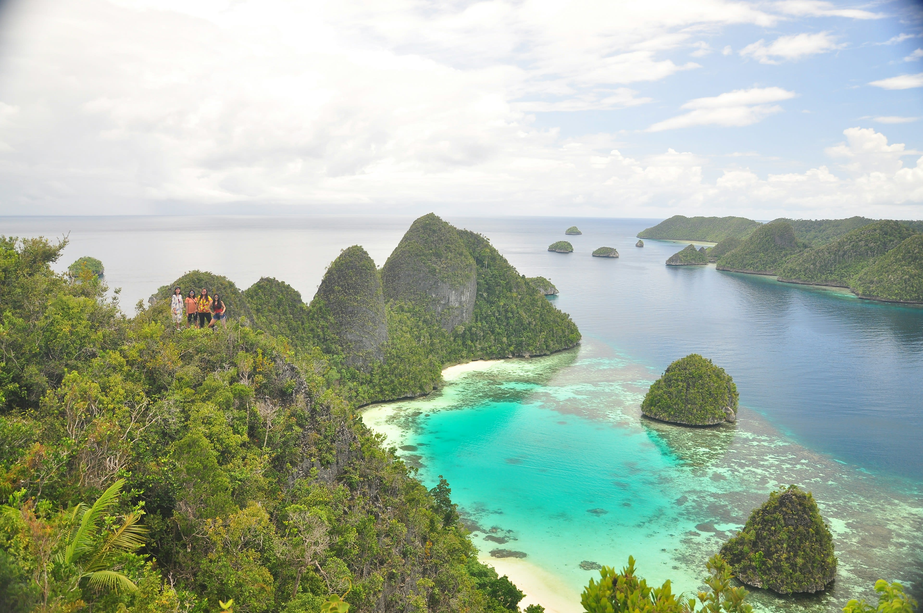 People standing on a karst viewpoint above islands and lagoon