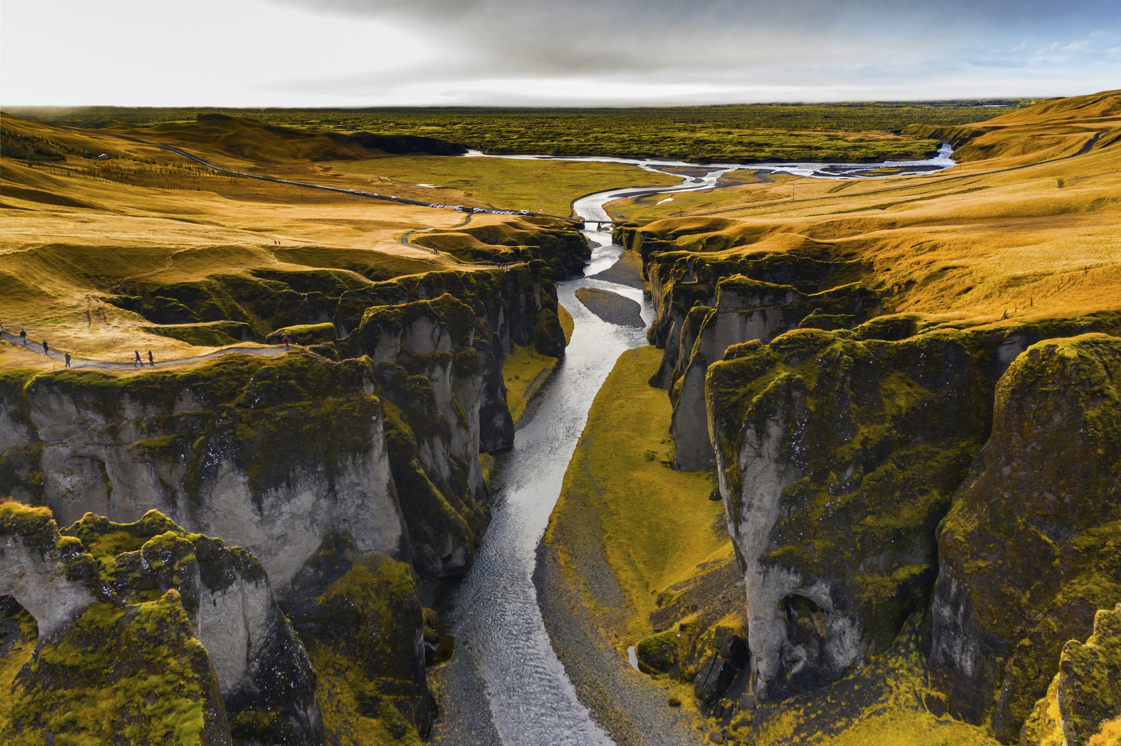 A moss-walled canyon with turquoise water threading along its floor, seen from above