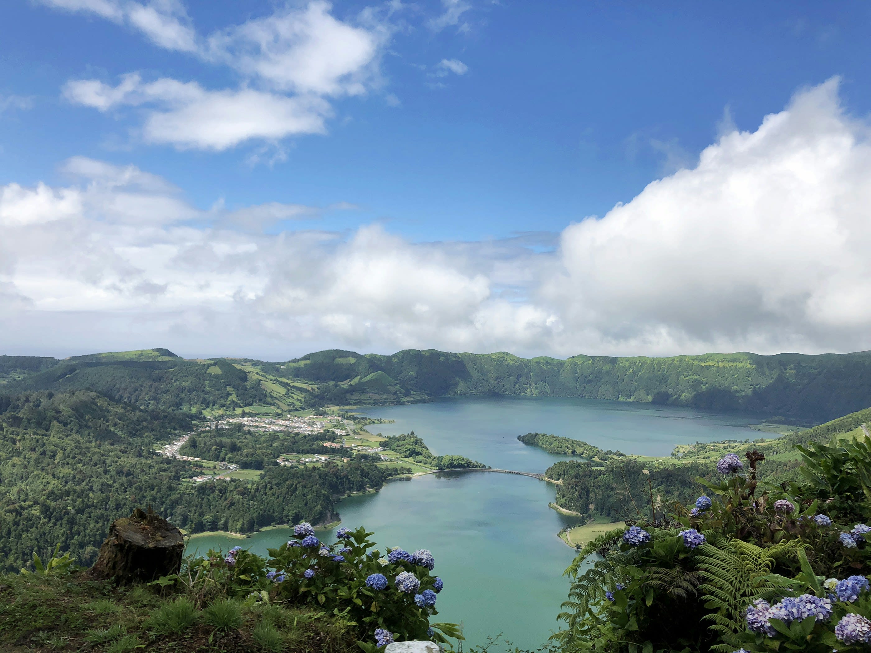 Two joined crater lakes of different colours surrounded by steep green slopes
