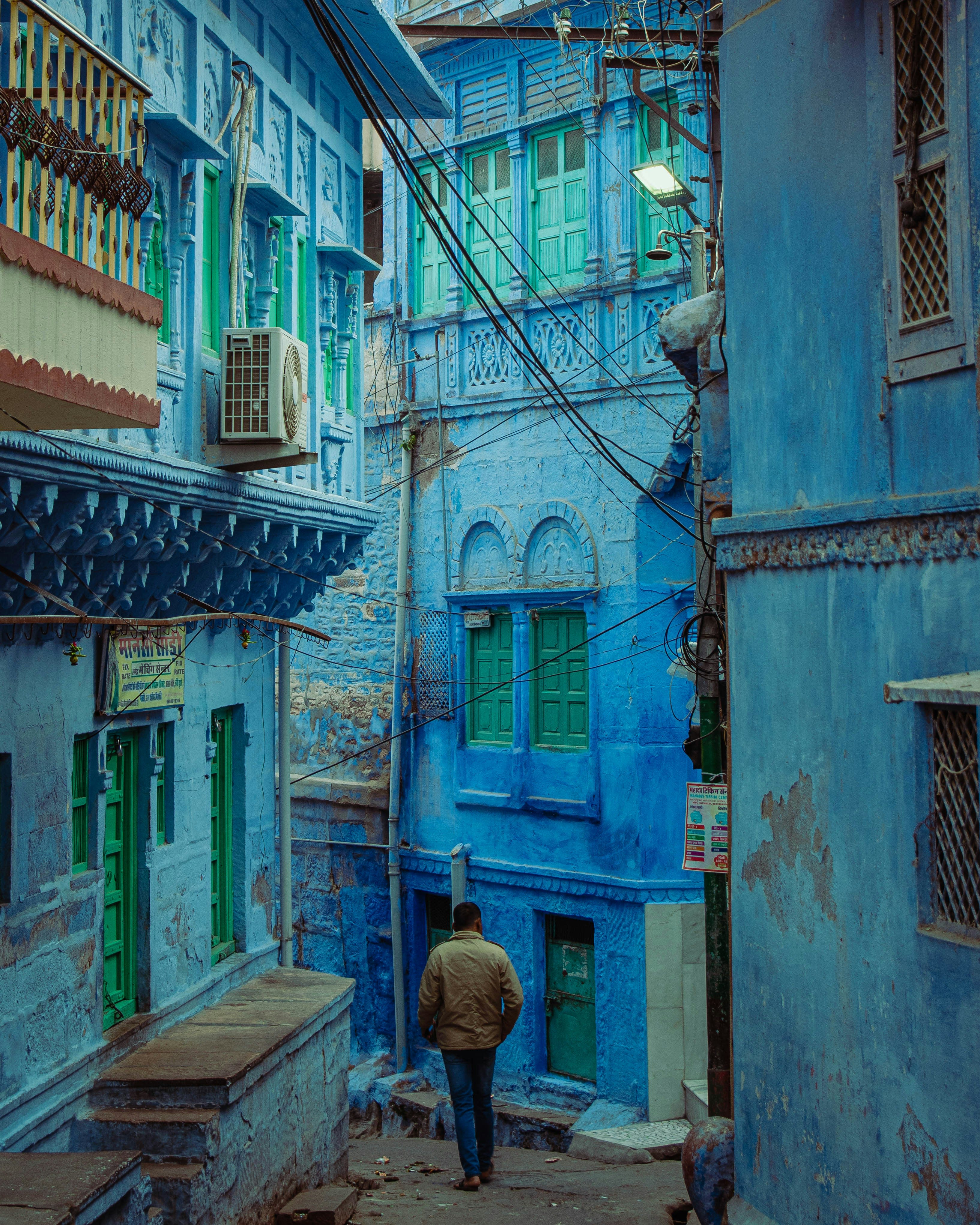 A person seated in a lane of vividly blue-painted houses