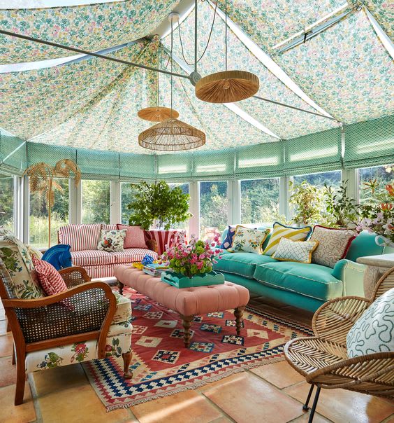 Conservatory with a floral fabric ceiling, pink and teal sofas and a red patterned rug